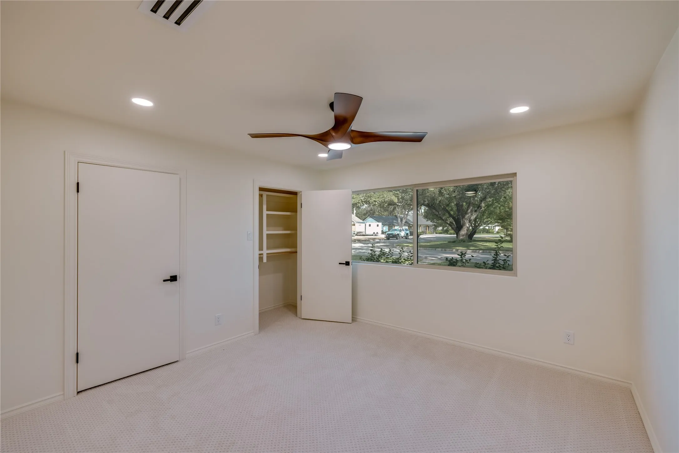 Spacious room featuring neutral carpeting, recessed lighting, and a modern ceiling fan
