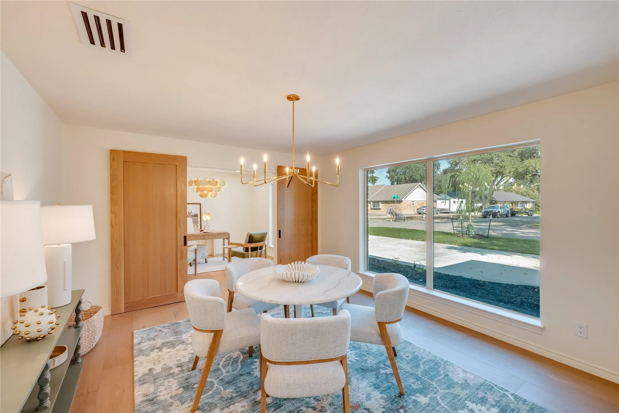 Spacious dining area featuring wood-finish flooring, a contemporary chandelier, and a large picture window