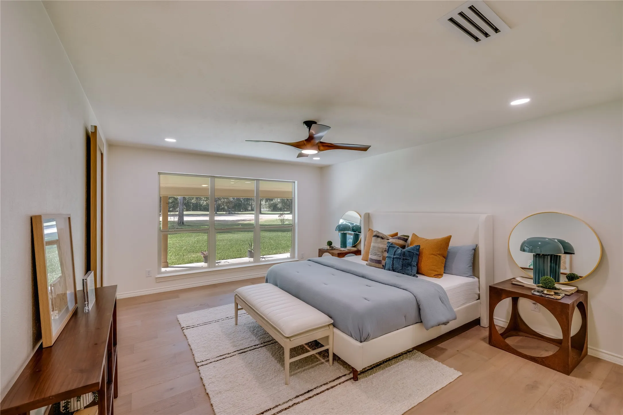 Primary bedroom featuring wood-finish flooring, a contemporary ceiling fan, recessed lighting, and a large multi-pane window