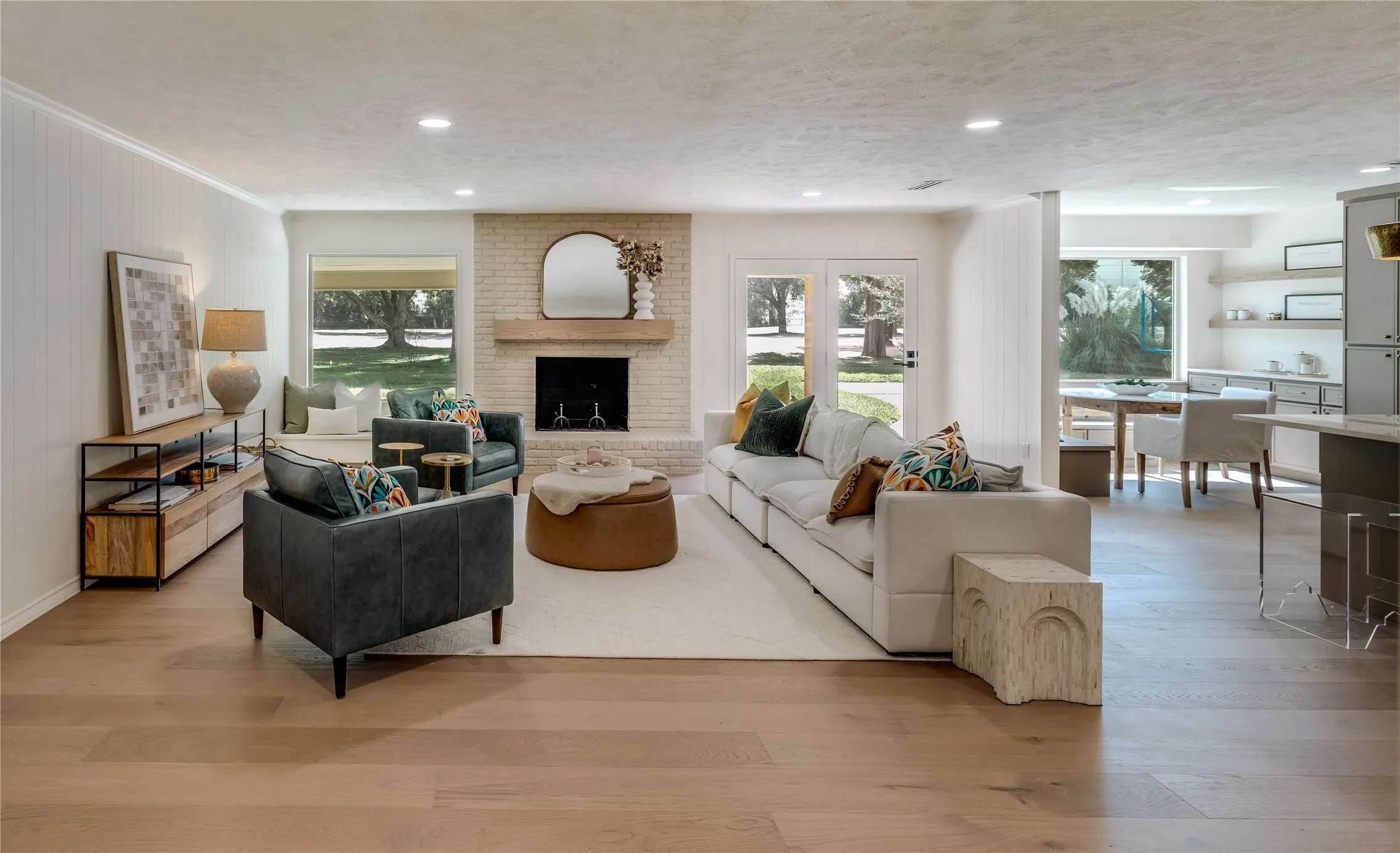 Spacious living area featuring wood-finish flooring, a brick fireplace with a wood mantel, and recessed lighting