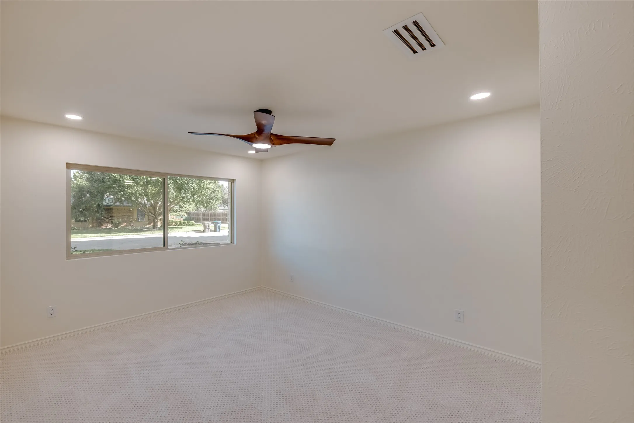 Carpeted room featuring a large window, recessed lighting, and a contemporary ceiling fan