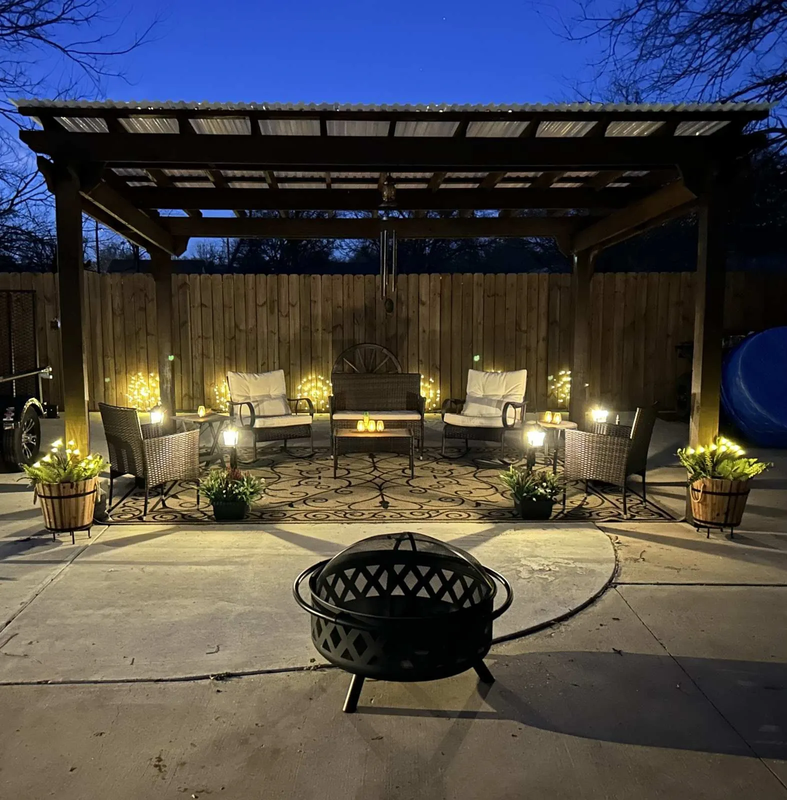 Expansive outdoor patio with a covered pergola featuring a corrugated roof, concrete flooring, and a privacy fence