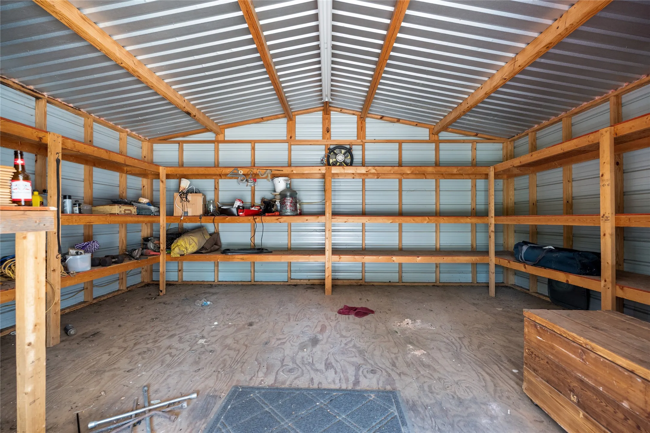 Metal corrugated roof, exposed wood beam framing, built-in wooden shelving, corrugated metal walls, wooden workbench