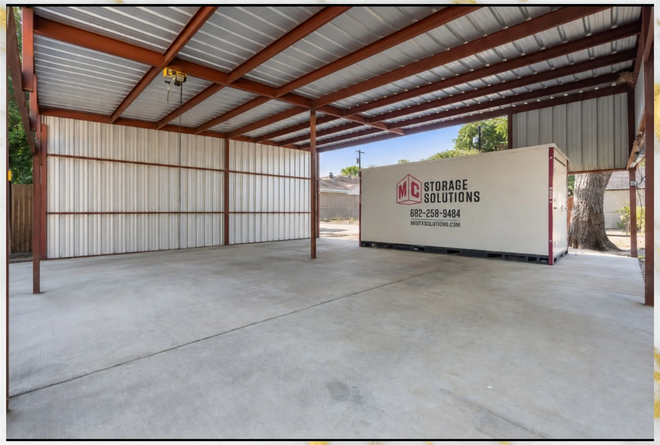 Covered concrete pad featuring a corrugated metal roof and exposed steel beam construction
