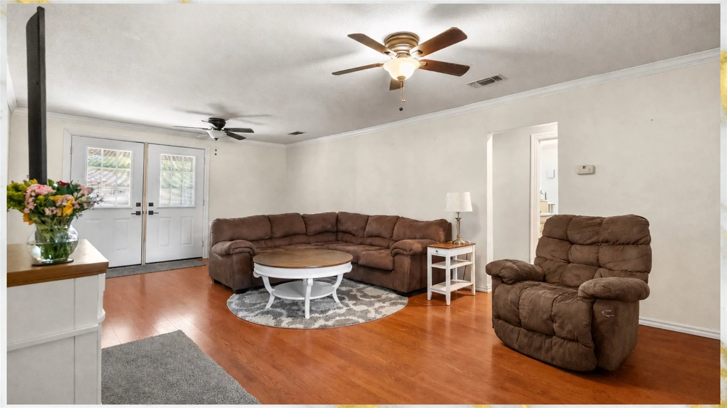 Warm-toned wood-finish flooring throughout, dual ceiling fans, and white interior walls