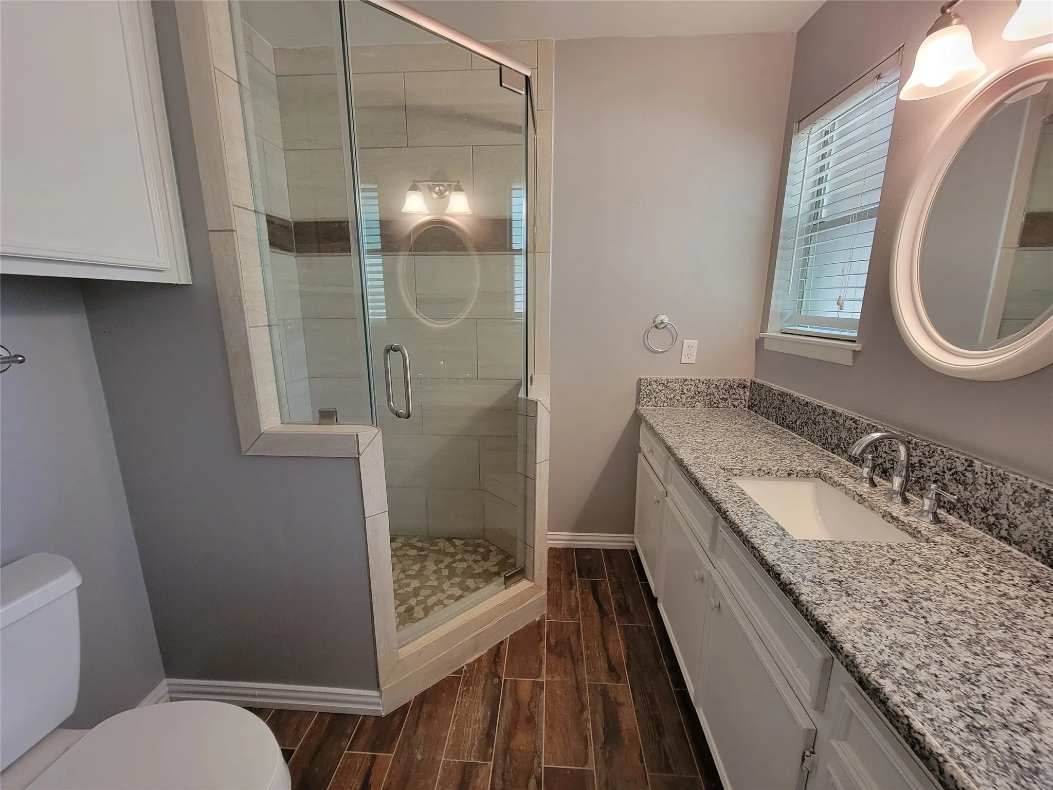 Glass-enclosed shower with pebble-tiled floor and tiled surround