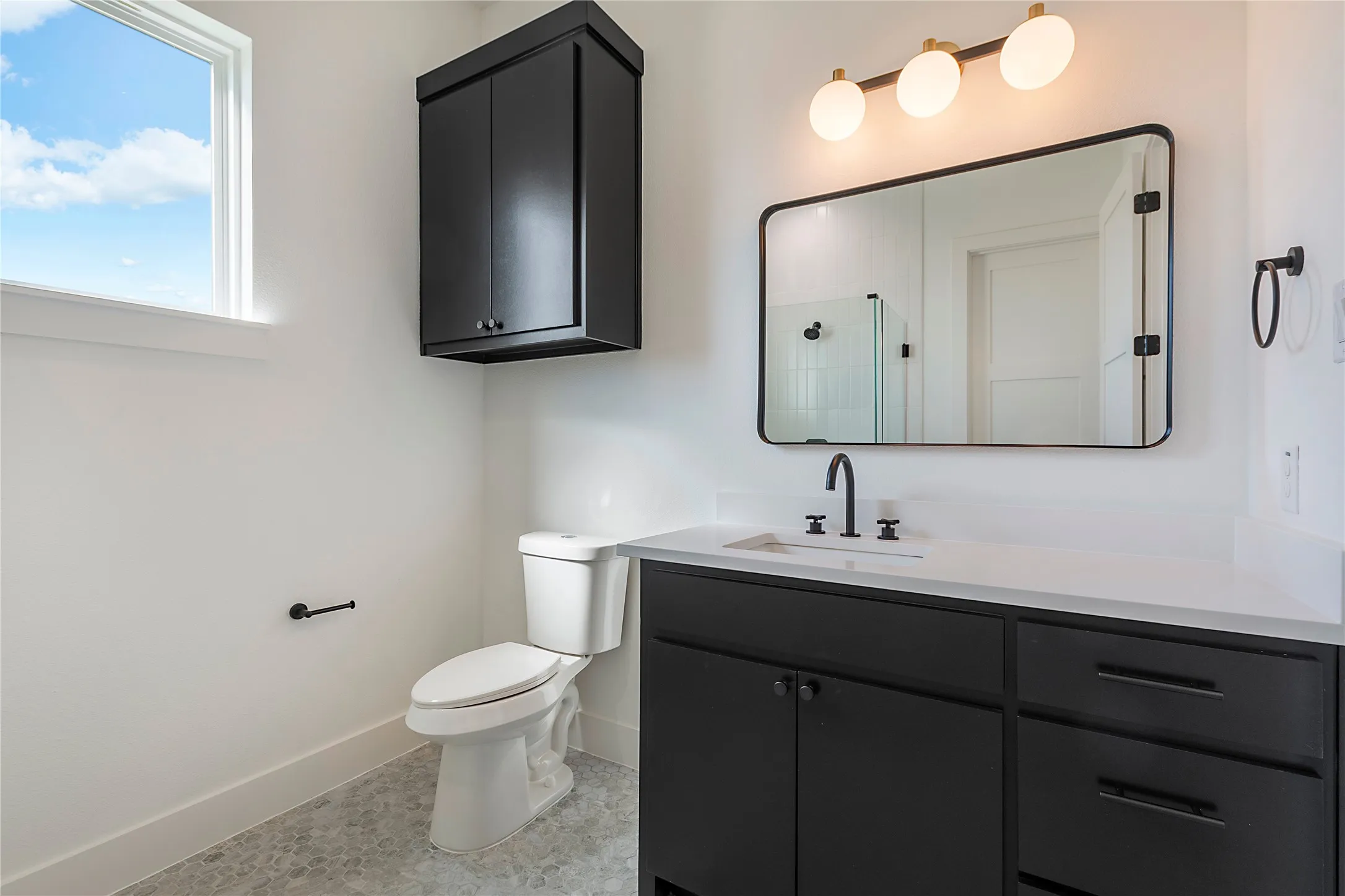 Vanity with white countertop and matte black hardware, framed mirror, and mosaic tile flooring