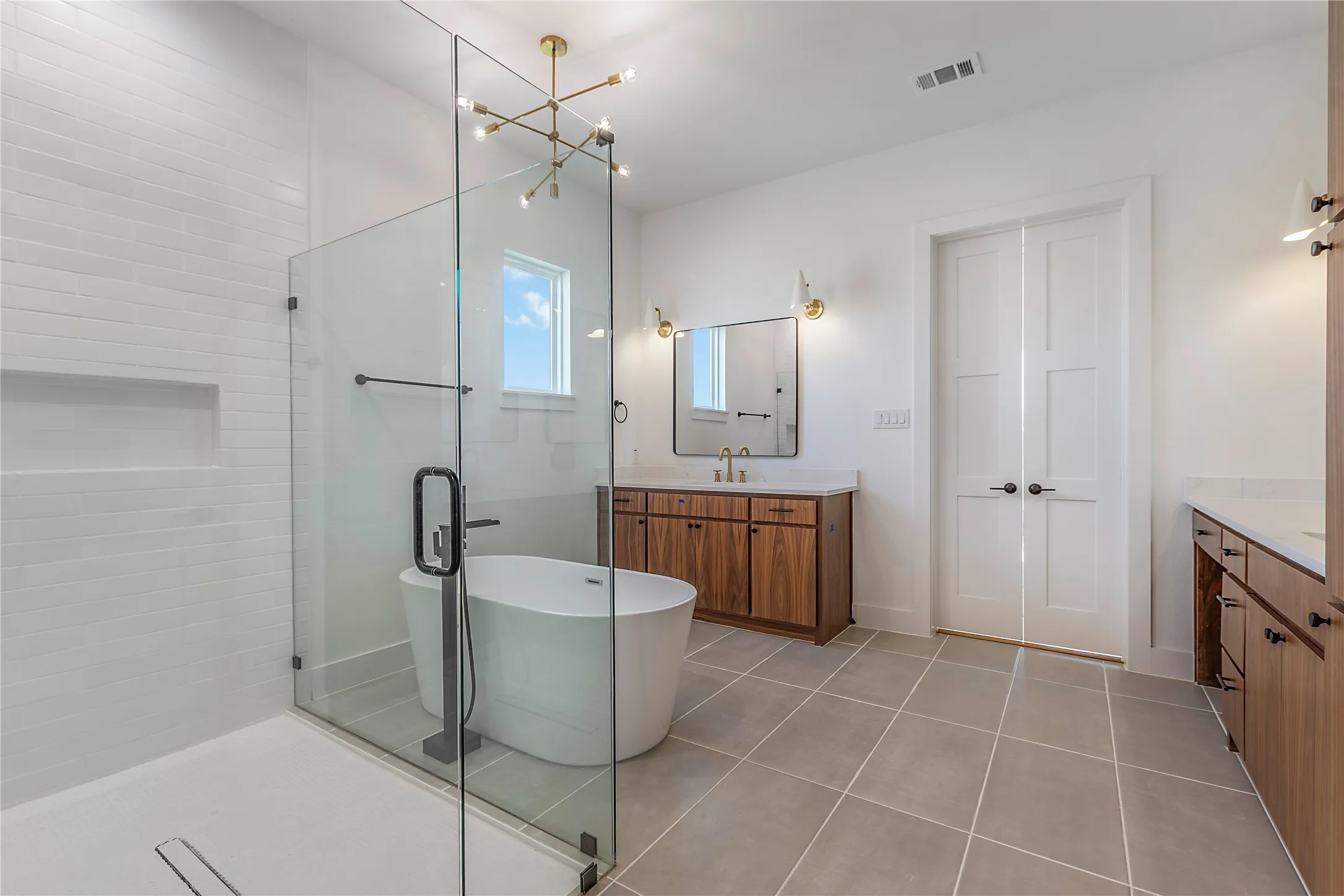 Glass-enclosed shower with white subway tile, a freestanding soaking tub, and a dual vanity with wood-finish cabinetry