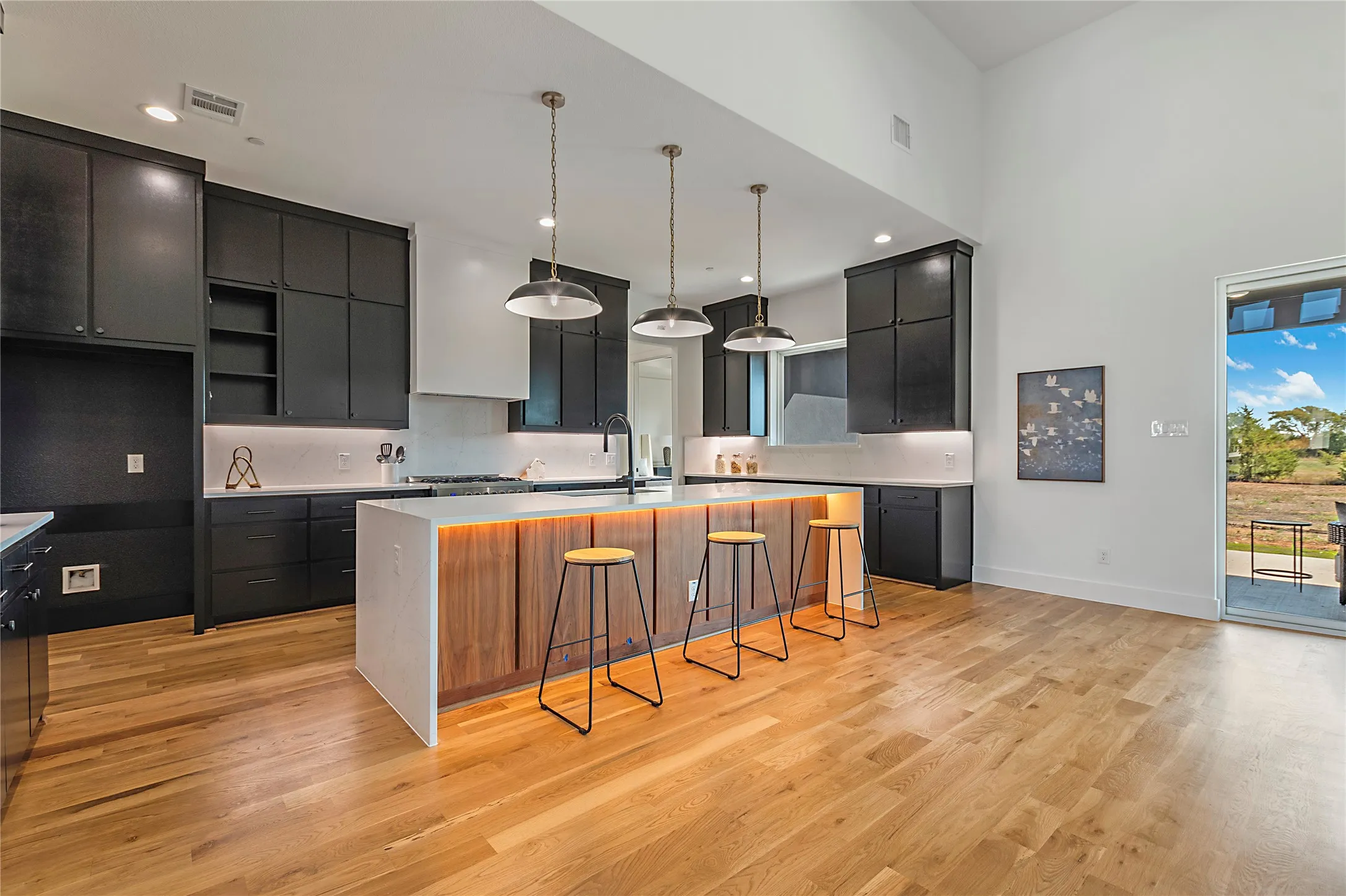 Spacious kitchen featuring hardwood flooring, dark cabinetry, and an expansive island with an integrated wood-finish base