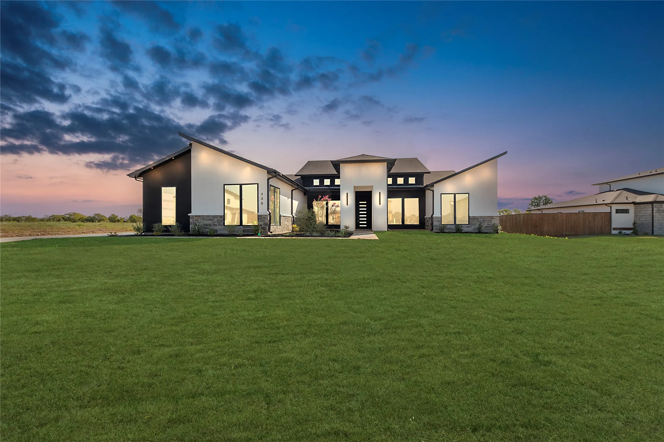 Contemporary architectural design with a prominent entryway, expansive glass panels, and stone veneer accents