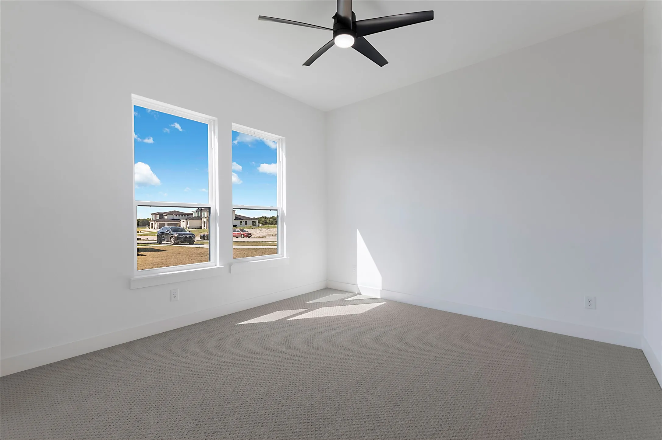 Dual windows, neutral wall paint, ceiling fan with light, and textured carpeting
