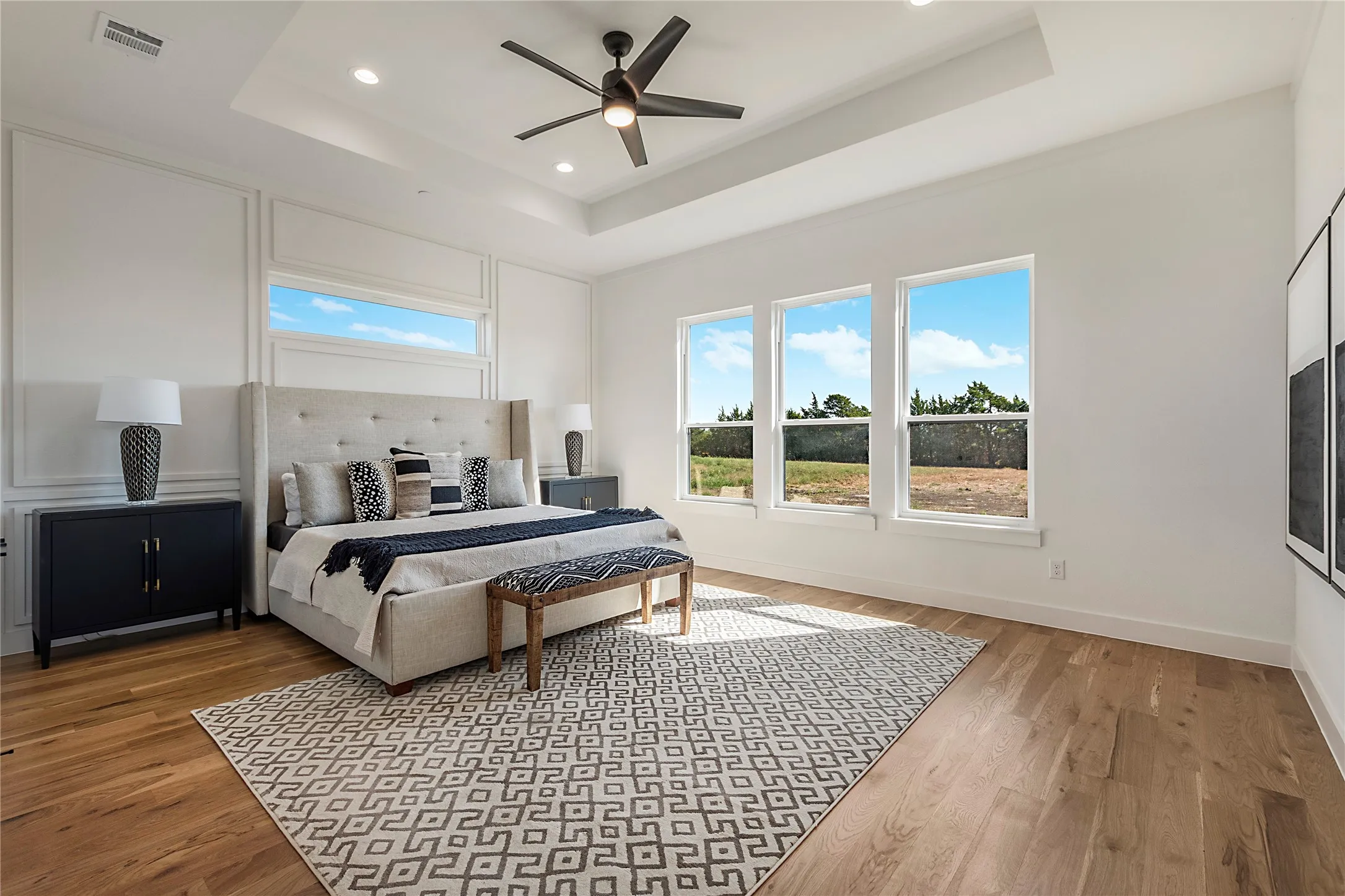 Tray ceiling with recessed lighting and a ceiling fan, wood-finish flooring, and multiple windows