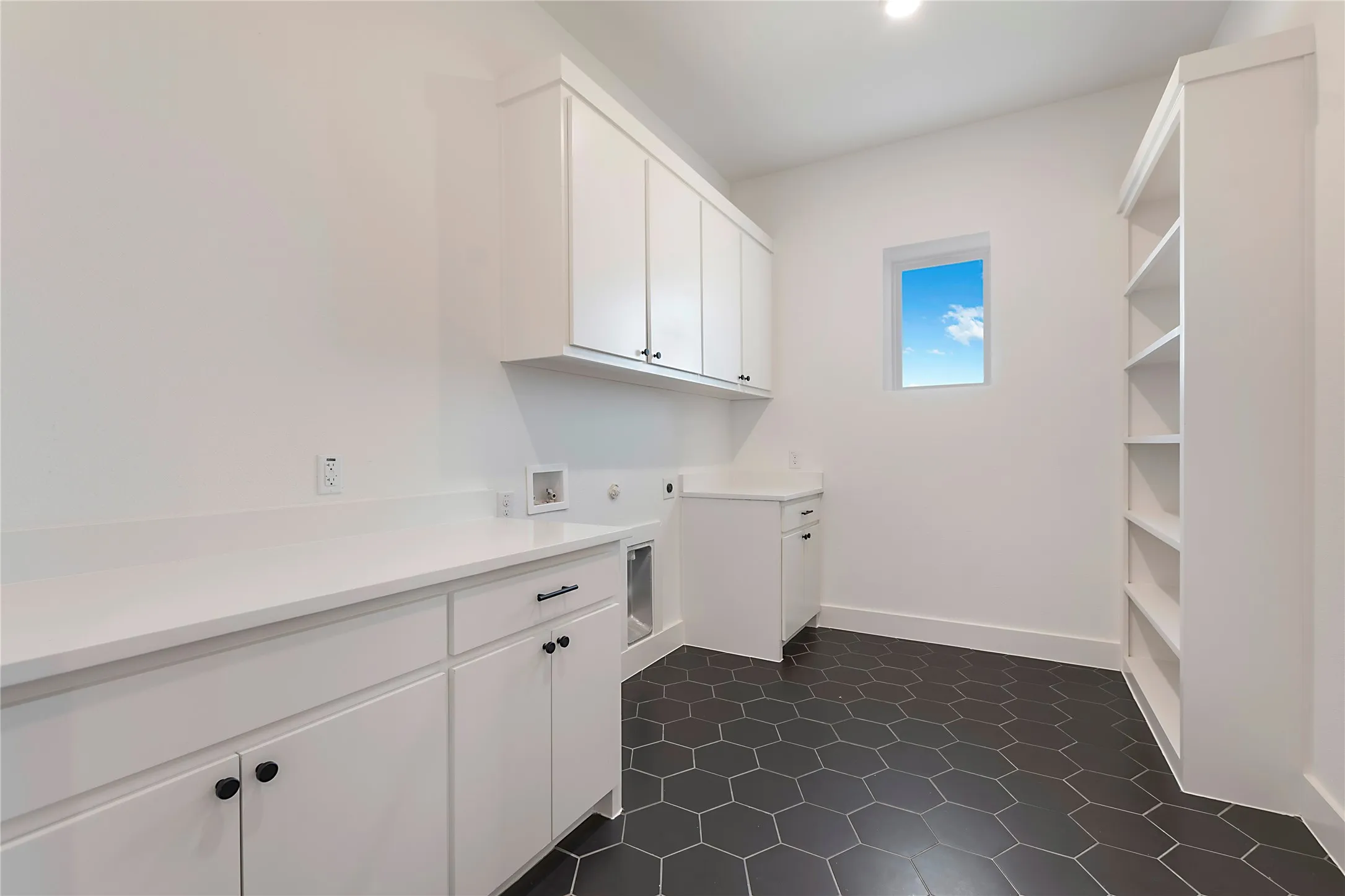 White shaker cabinetry with black hardware, white countertops, built-in shelving, and hexagonal floor tiling