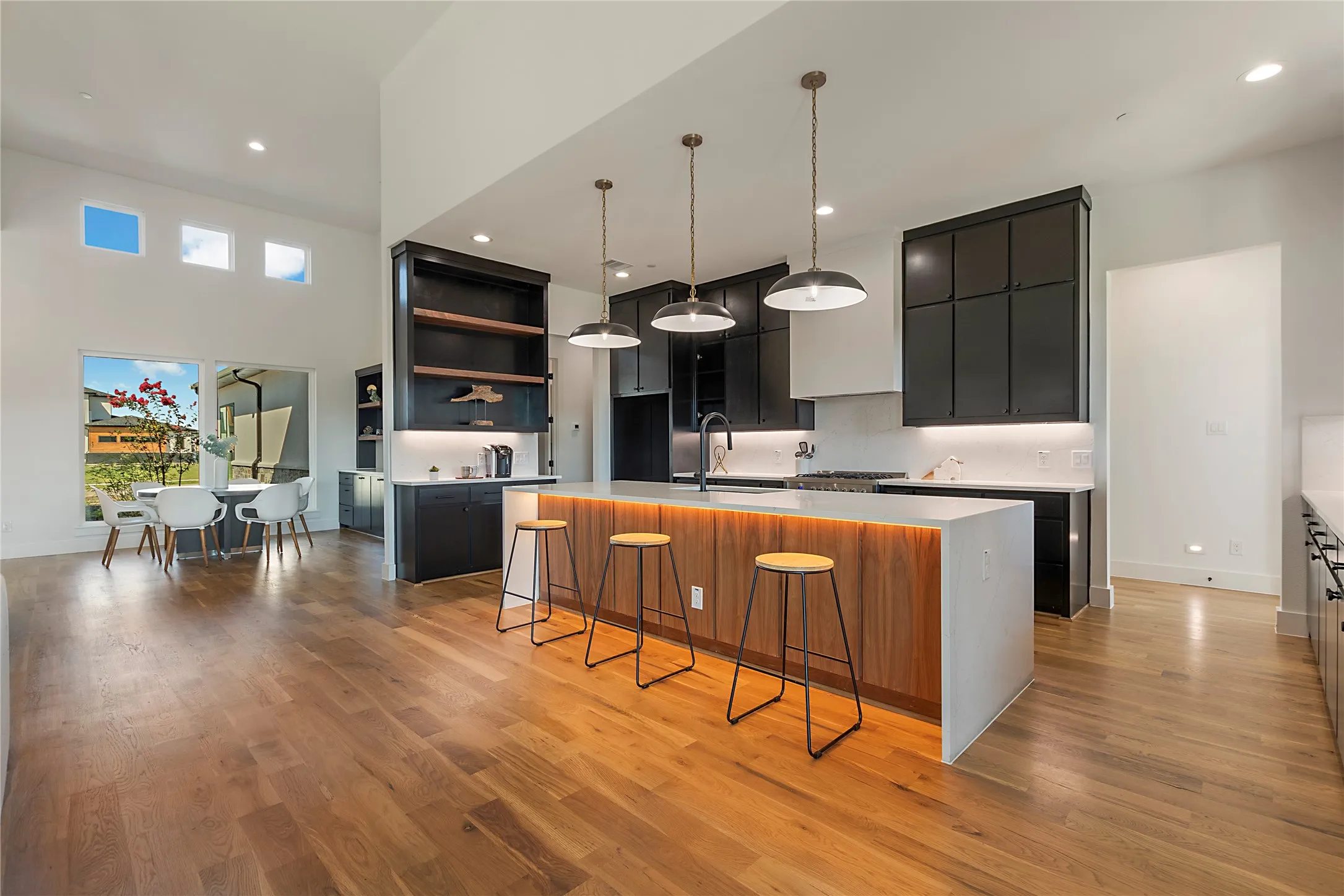 Vaulted ceilings, wood-finish flooring, custom built-in cabinetry, large central island, and multiple windows