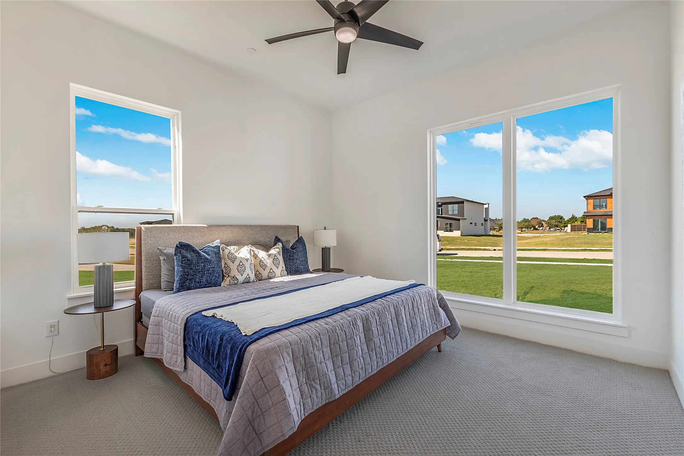 Vaulted ceiling with a ceiling fan, light gray carpet, and multiple large windows