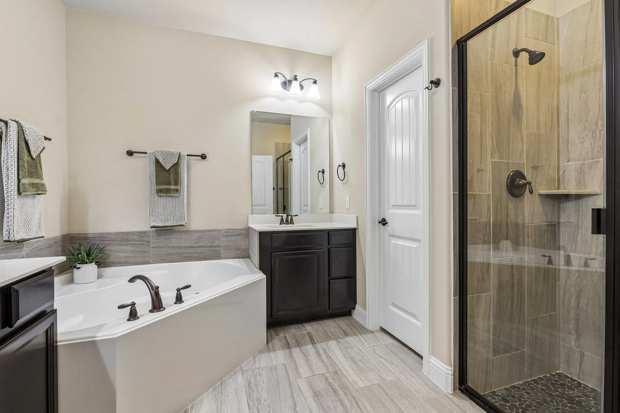 The ensuite primary bathroom has a separate glass enclosed shower and a corner tub