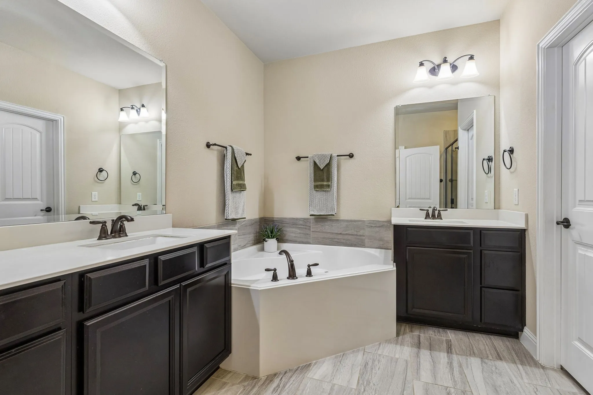 Dual dark wood-finish vanities with white countertops, integrated sinks, and bronze-finish fixtures