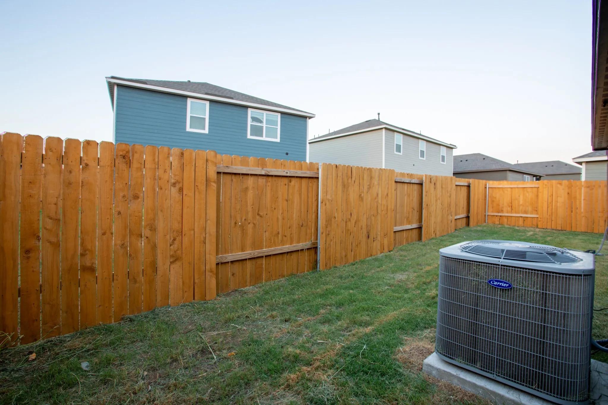 Fenced yard with a grassy area and an outdoor HVAC unit on a concrete pad