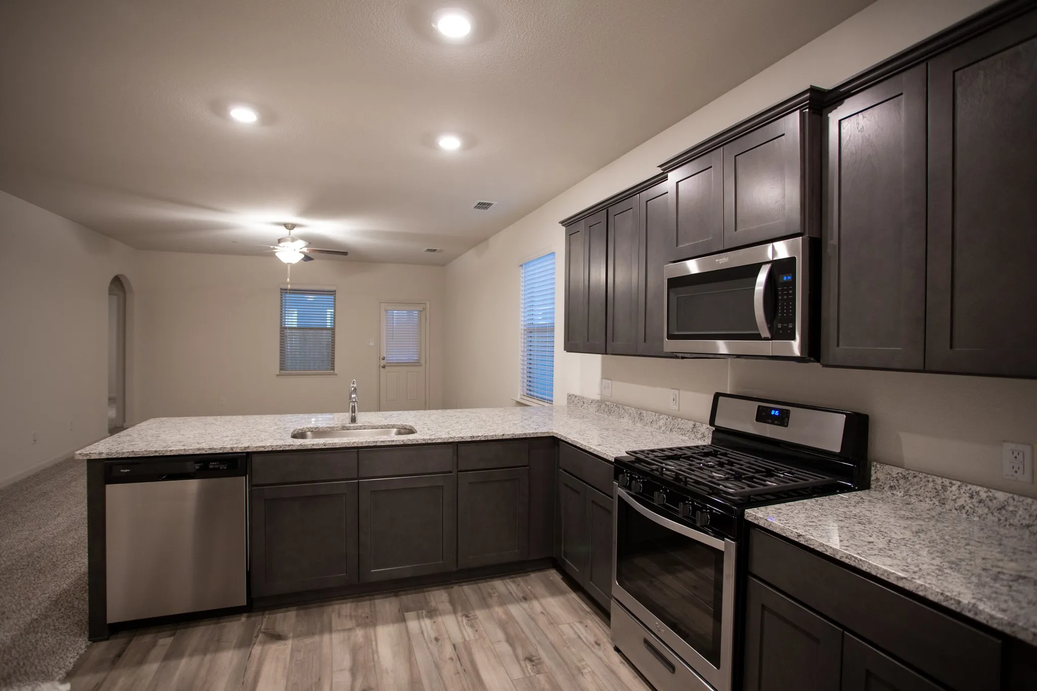 Kitchen featuring dark wood-finish cabinetry, light-toned countertops, stainless steel appliances, and wood-finish flooring