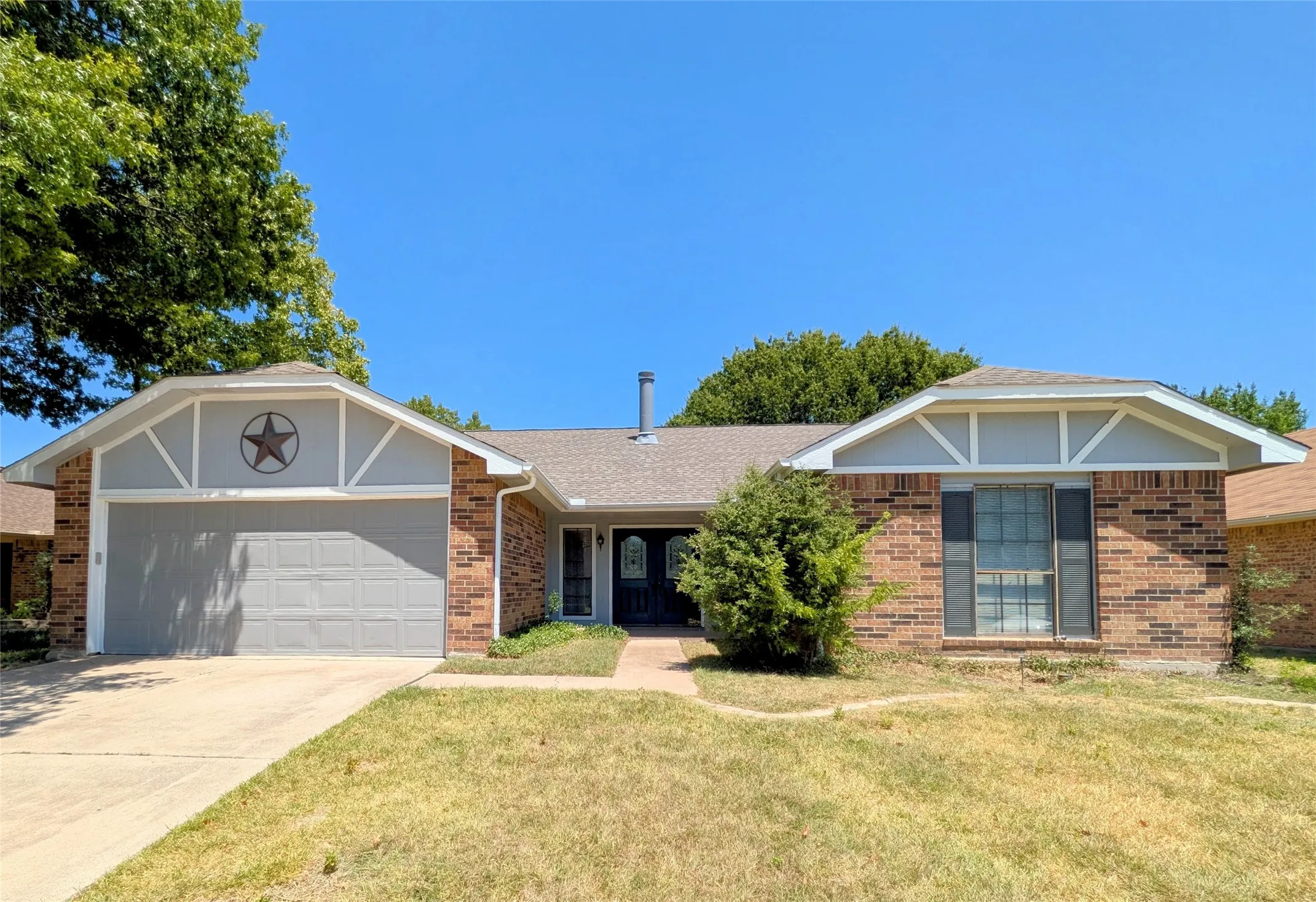 Brick exterior with light gray siding accents, attached garage, and a concrete driveway