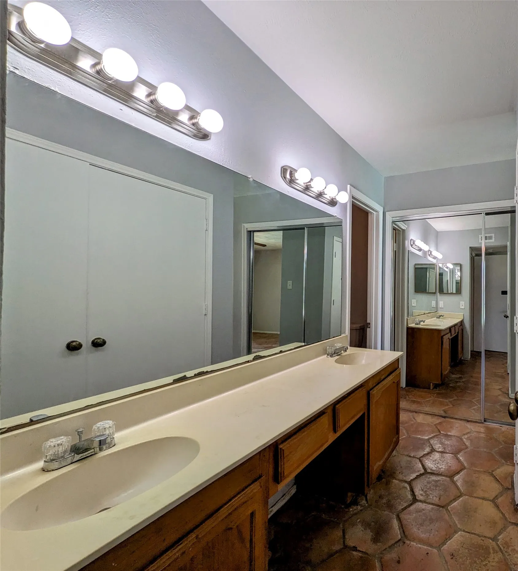 Dual vanity with integrated sinks, wood-finish cabinetry, and hexagon tile flooring