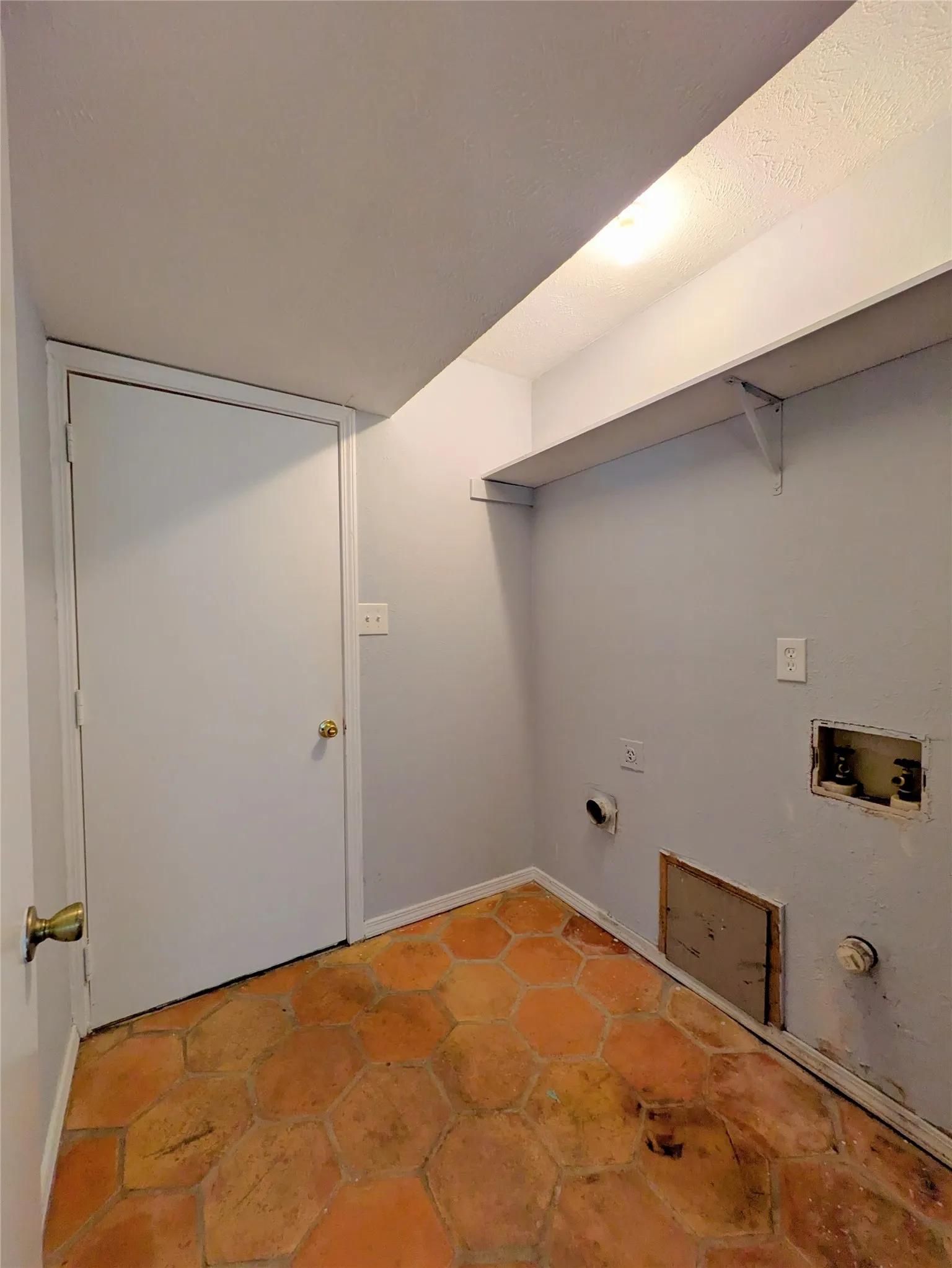 Hexagonal terracotta-style floor tiles, built-in shelving, and light gray wall paint
