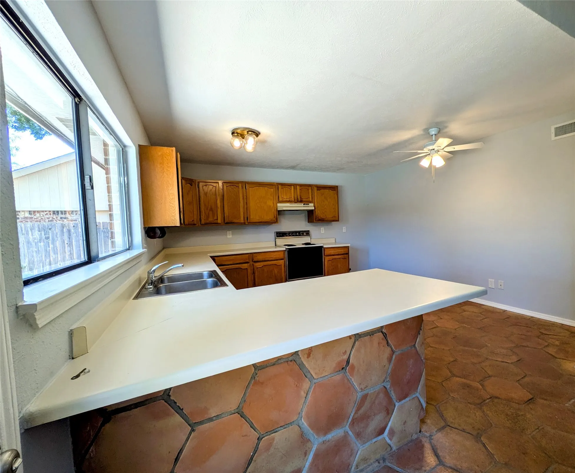 Kitchen featuring wood cabinetry, white countertops, a double basin sink, and a black range
