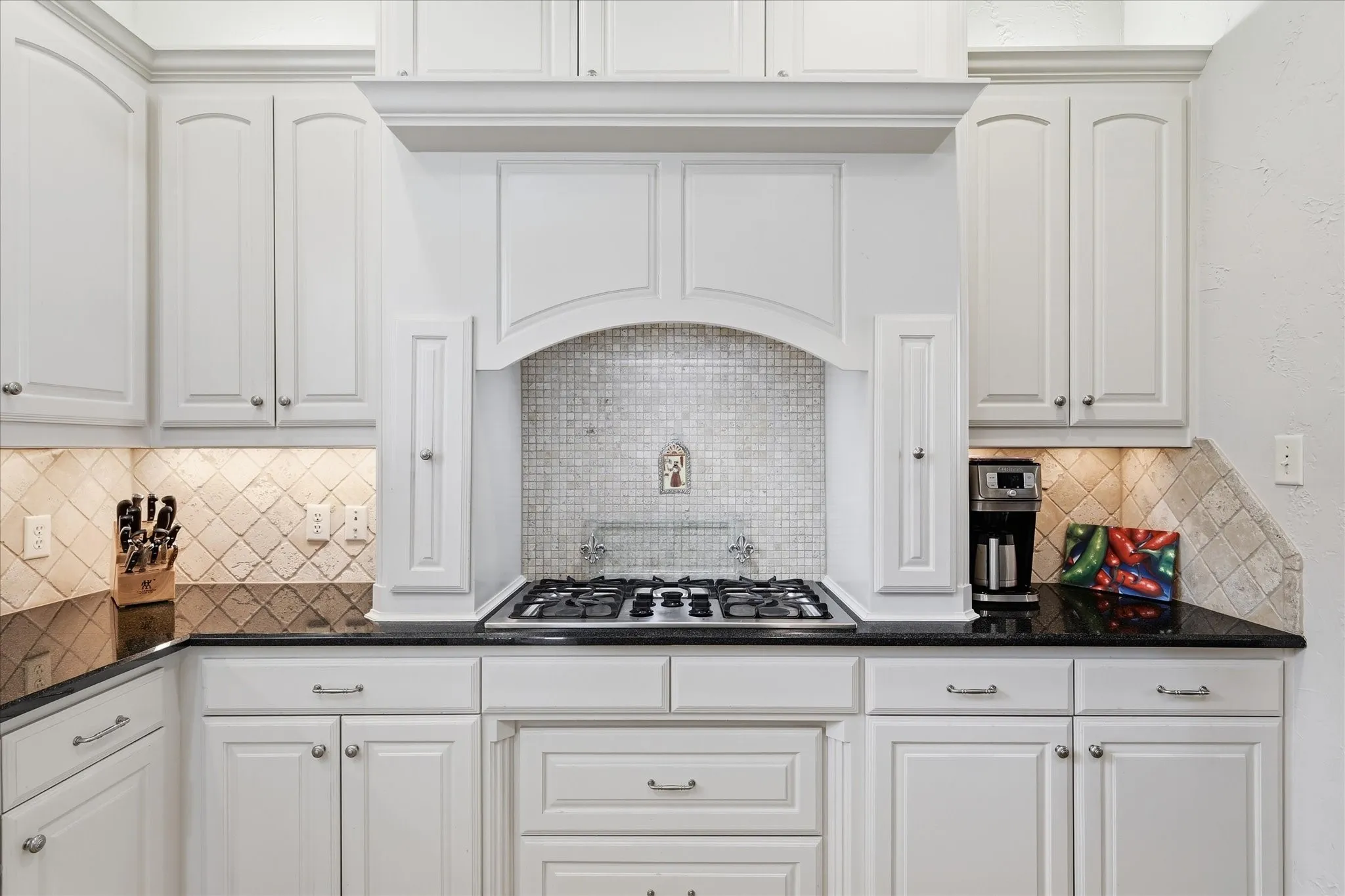 The gas cooktop is surrounded by beautiful painted cabinets and spice racks
