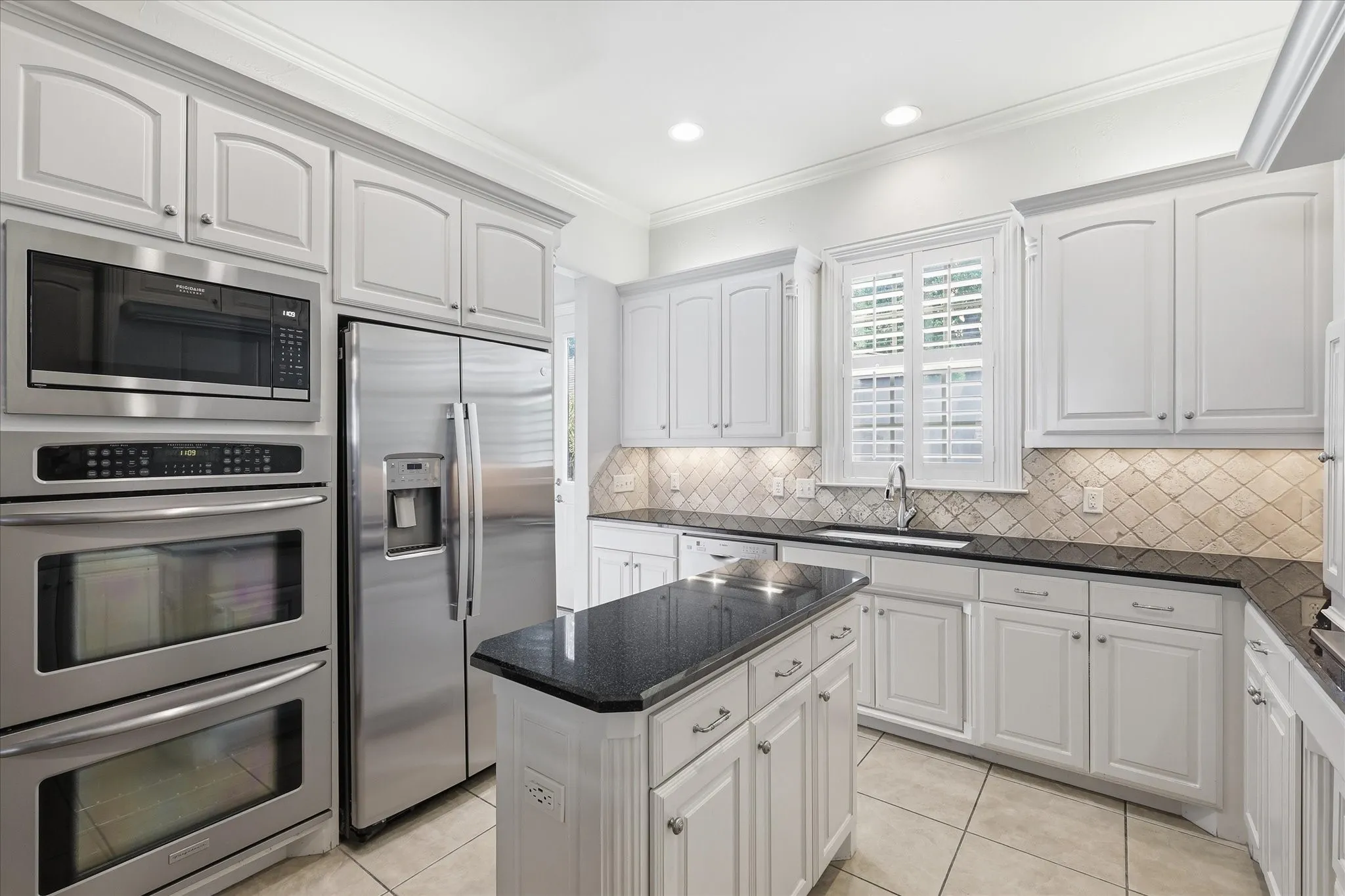 Another view of this stunning kitchen shows off the stainless steel double ovens microwave and refrigerator