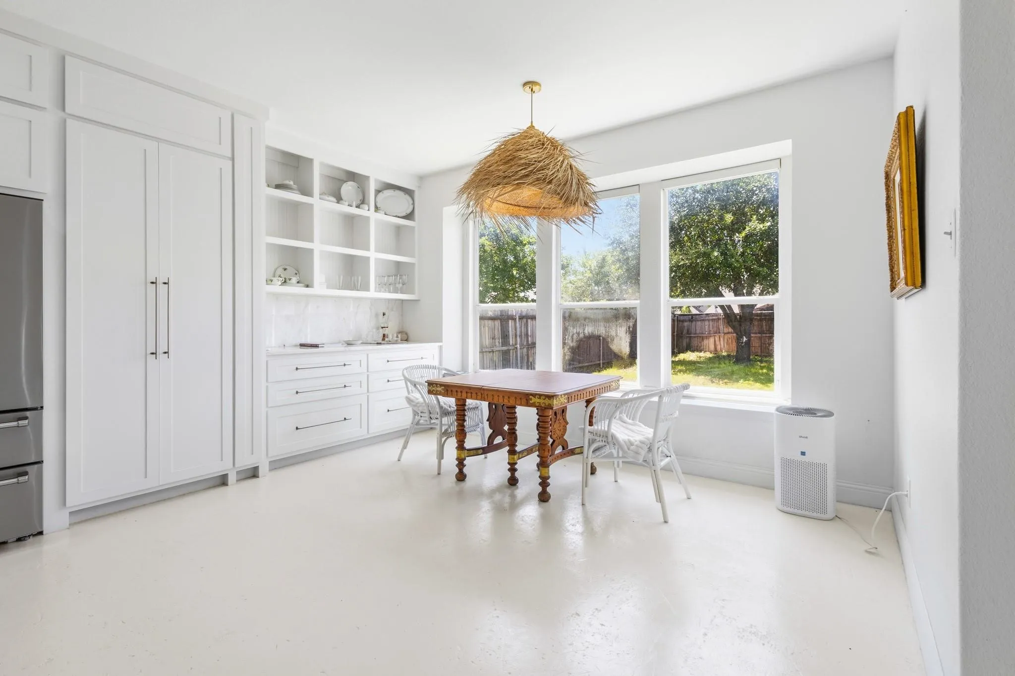 White shaker-style cabinetry with built-in shelving, a tiled backsplash, and light-toned flooring