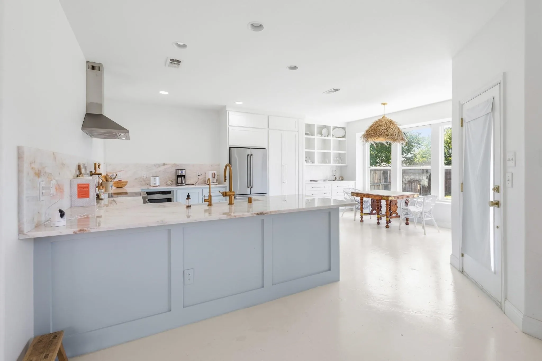 Kitchen featuring a large central island, stainless steel range hood, built-in shelving, ample natural light, and a dedicated dining area