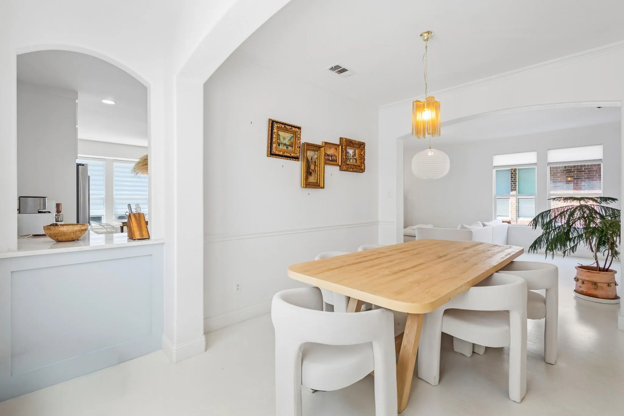 Arched doorways define the dining area, featuring a decorative chandelier and light wood-finish flooring