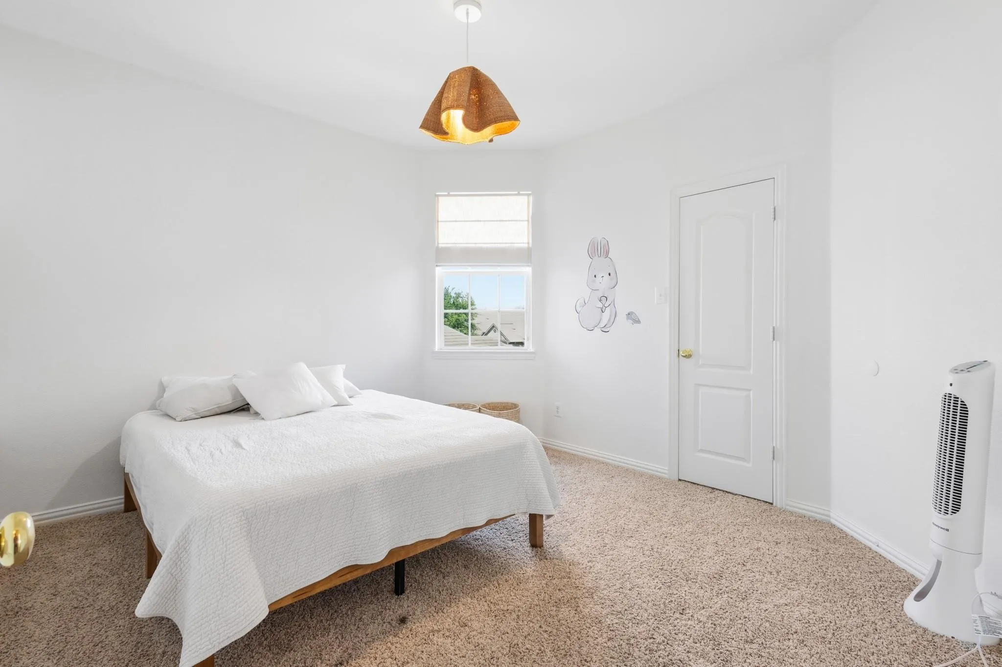 Crisp white walls, neutral carpeting, window with blinds, modern pendant light fixture, and a white interior door