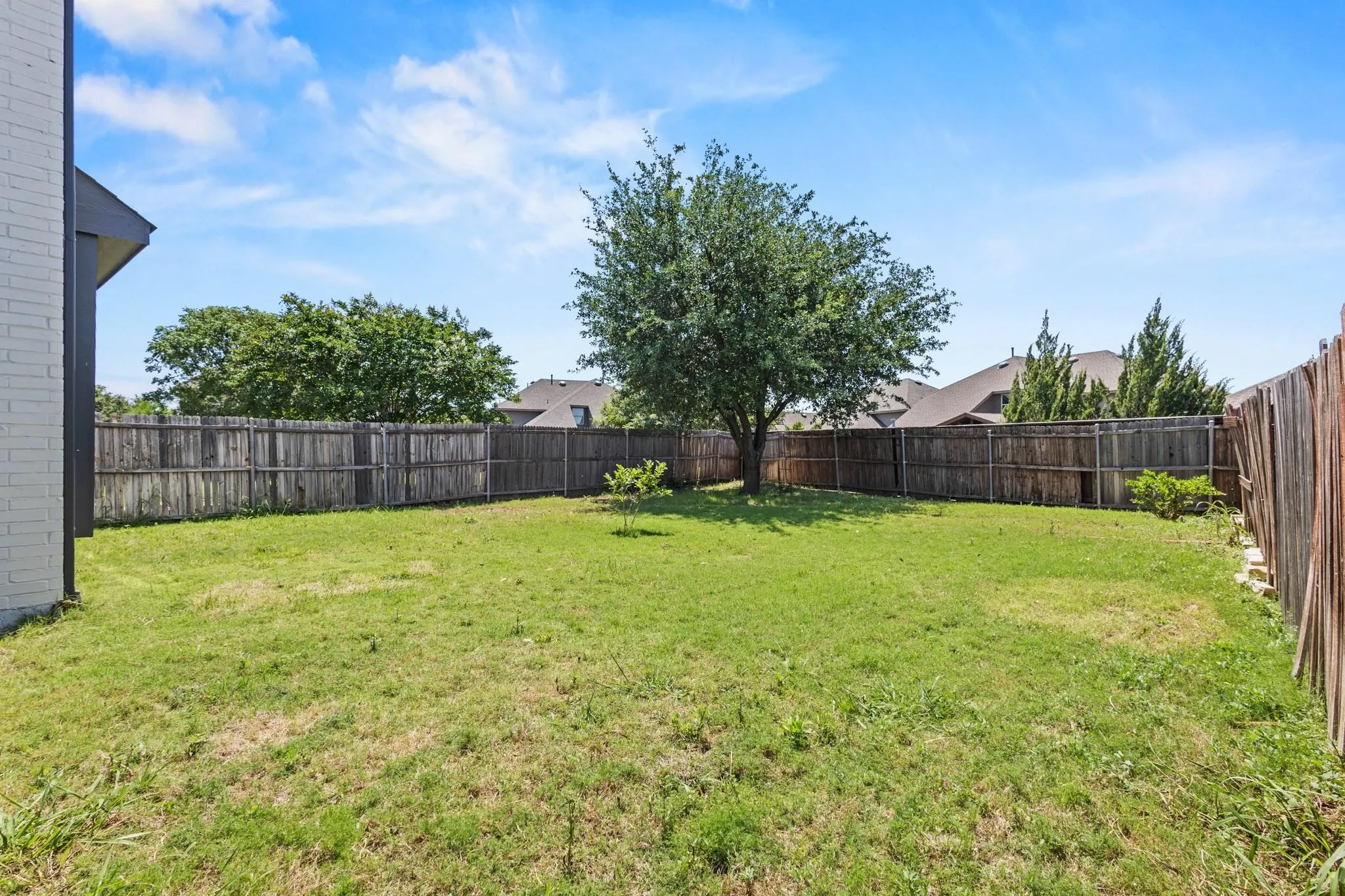 Fenced rear yard with a mature shade tree and established lawn