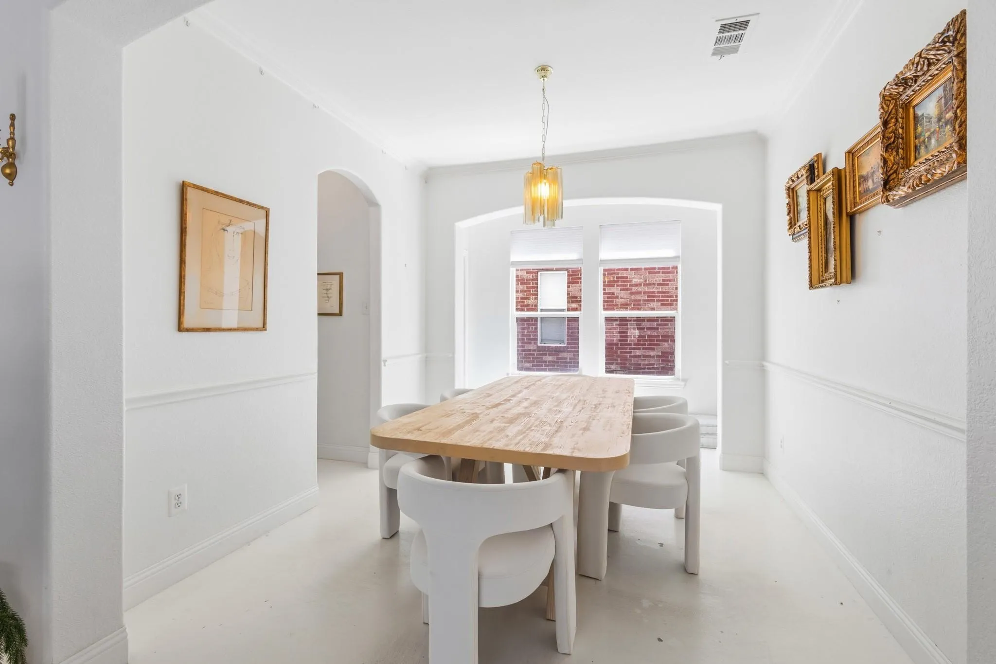 Arched entryway, crown molding, chair rail molding, ceiling-mounted light fixture, window with brick exterior visibility