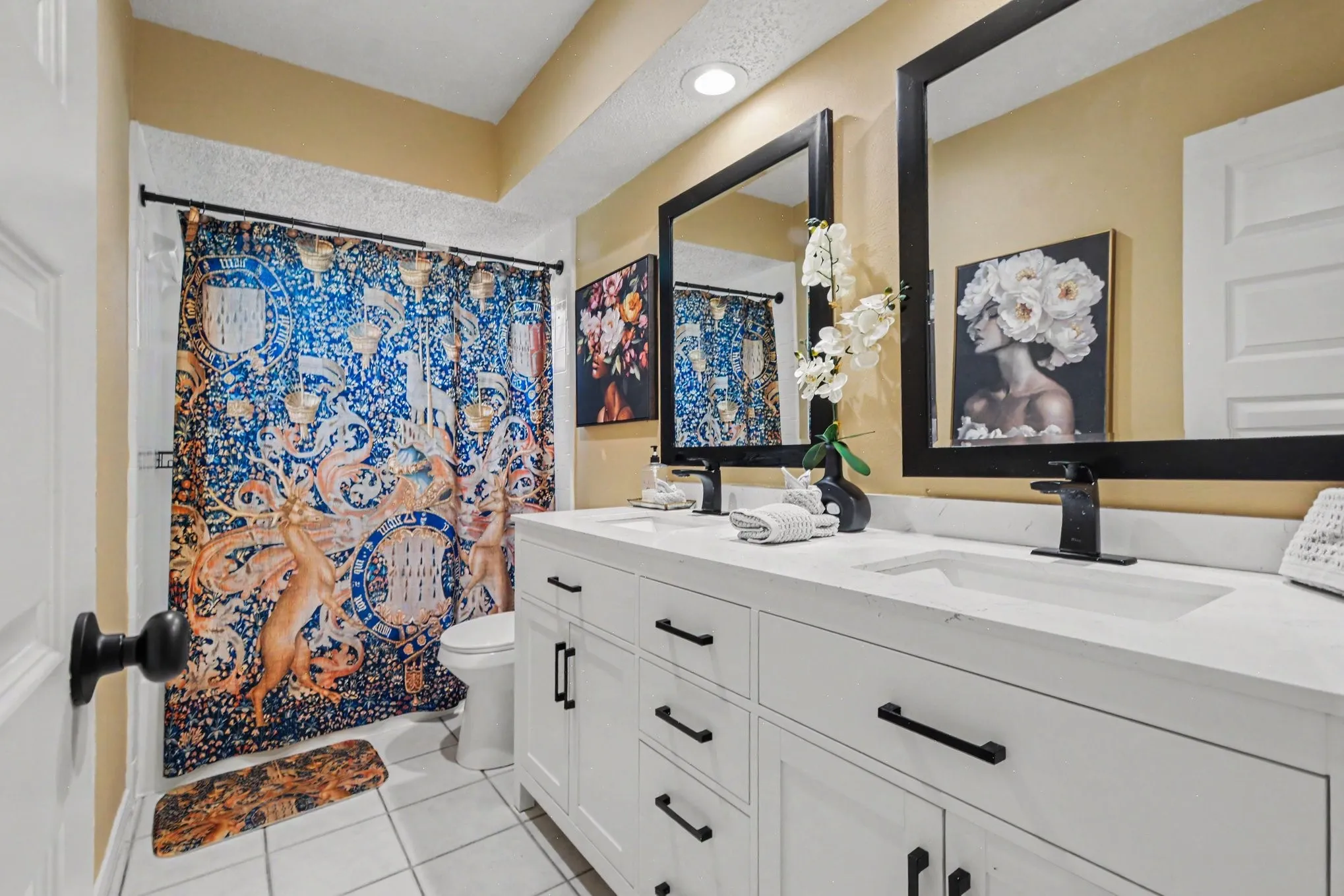 Double vanity with white cabinetry and matte black hardware, dual rectangular undermount sinks, and black framed mirrors