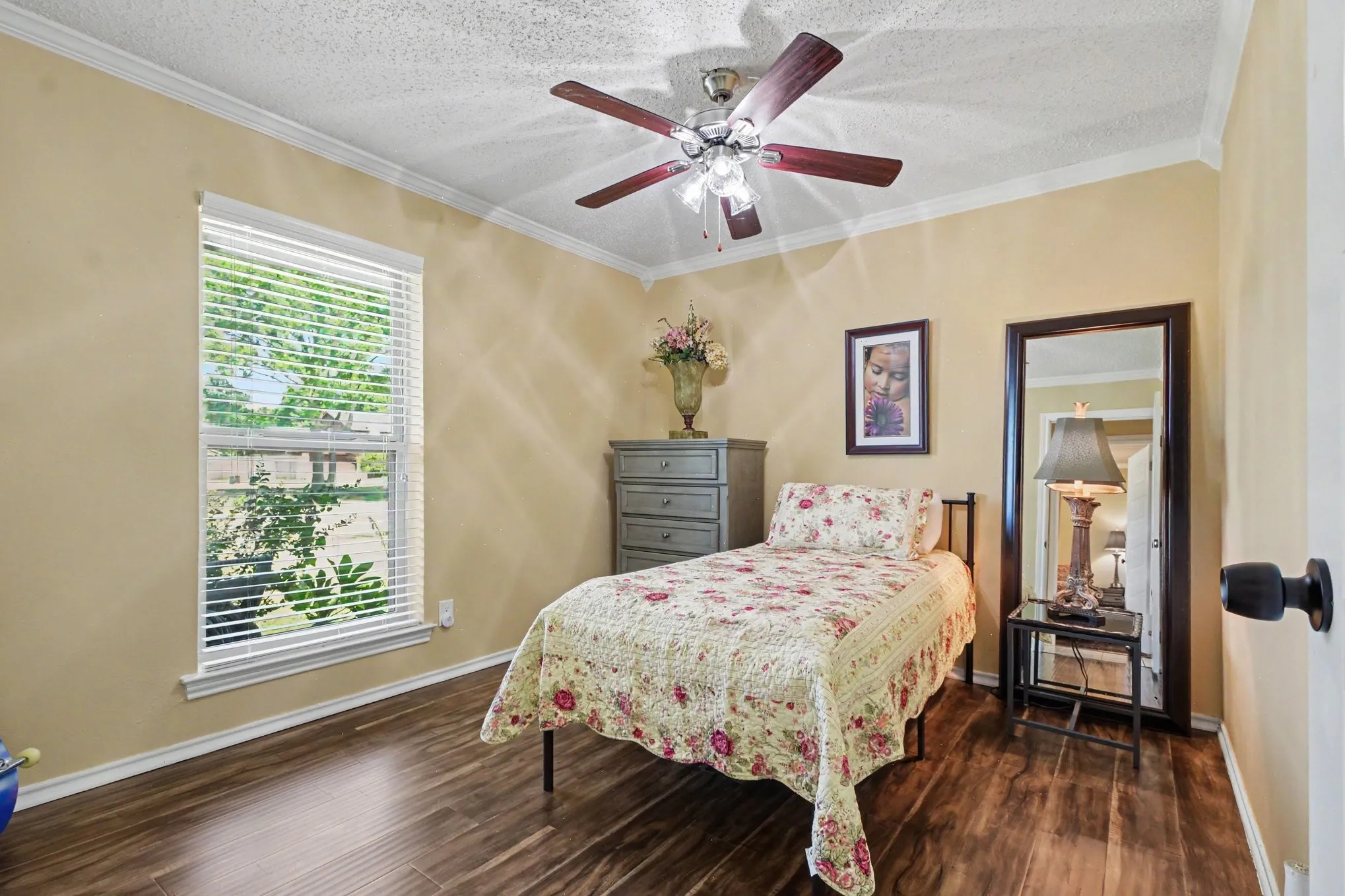 Wood-finish flooring, crown molding, and a ceiling fan with integrated lighting