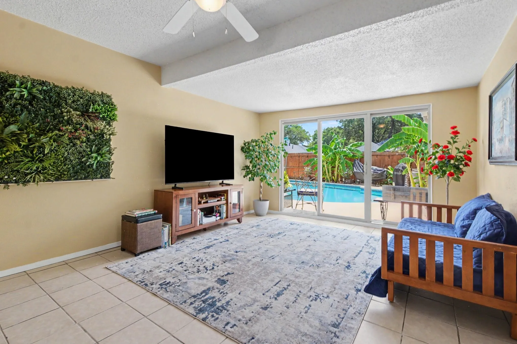 Tiled flooring, ceiling fan, sliding glass doors, and a visible pool