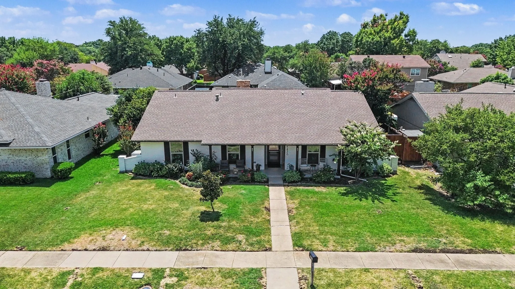 Aerial view highlighting the home's front elevation, driveway, and landscaped yard.