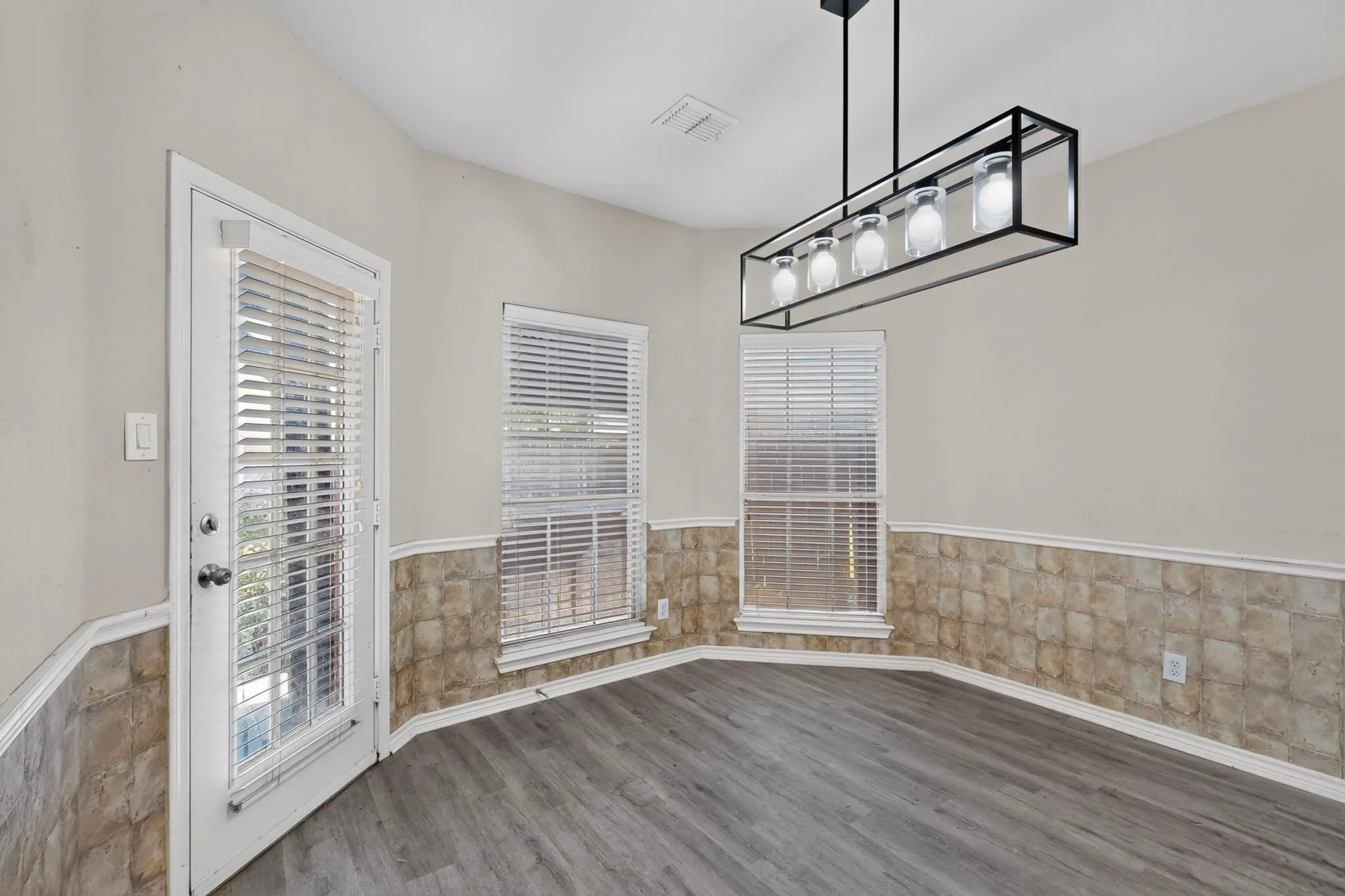 Wood-finish flooring, half-wall wainscoting, and a multi-pane glass door