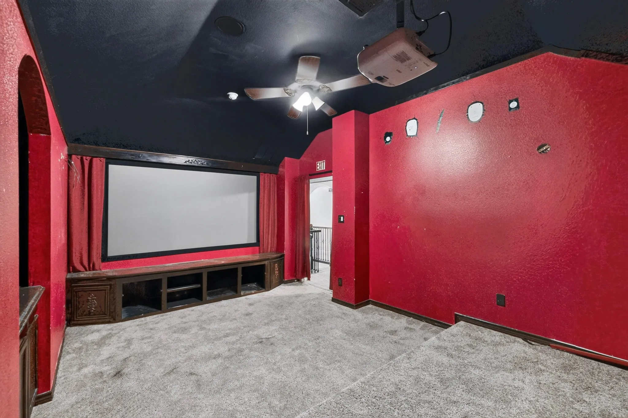 Dedicated media room featuring a large projector screen, built-in entertainment console, and tiered flooring