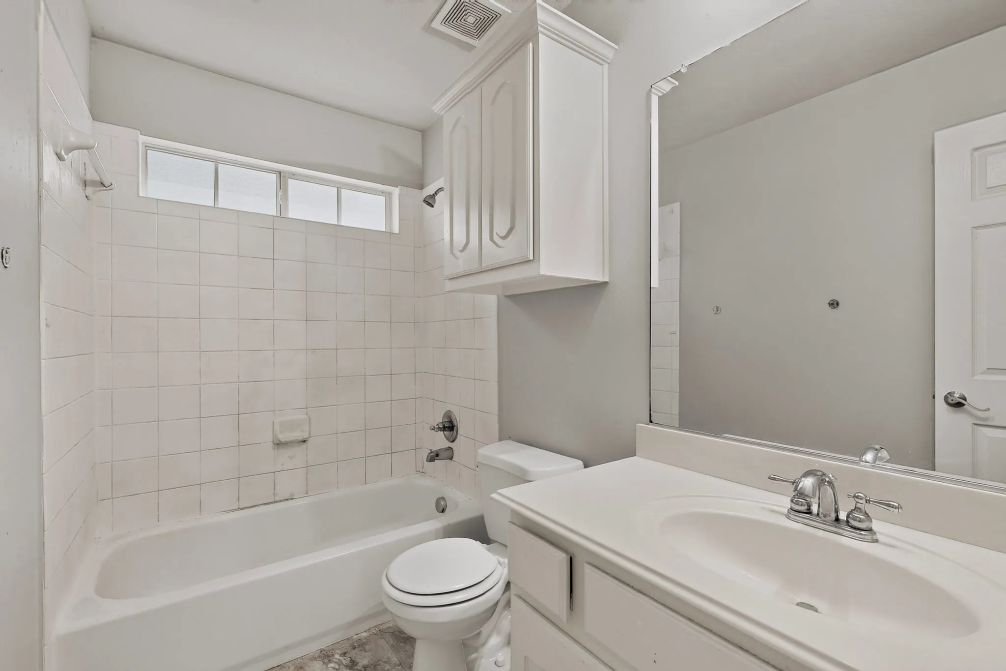 White tiled bath/shower combination with chrome fixtures