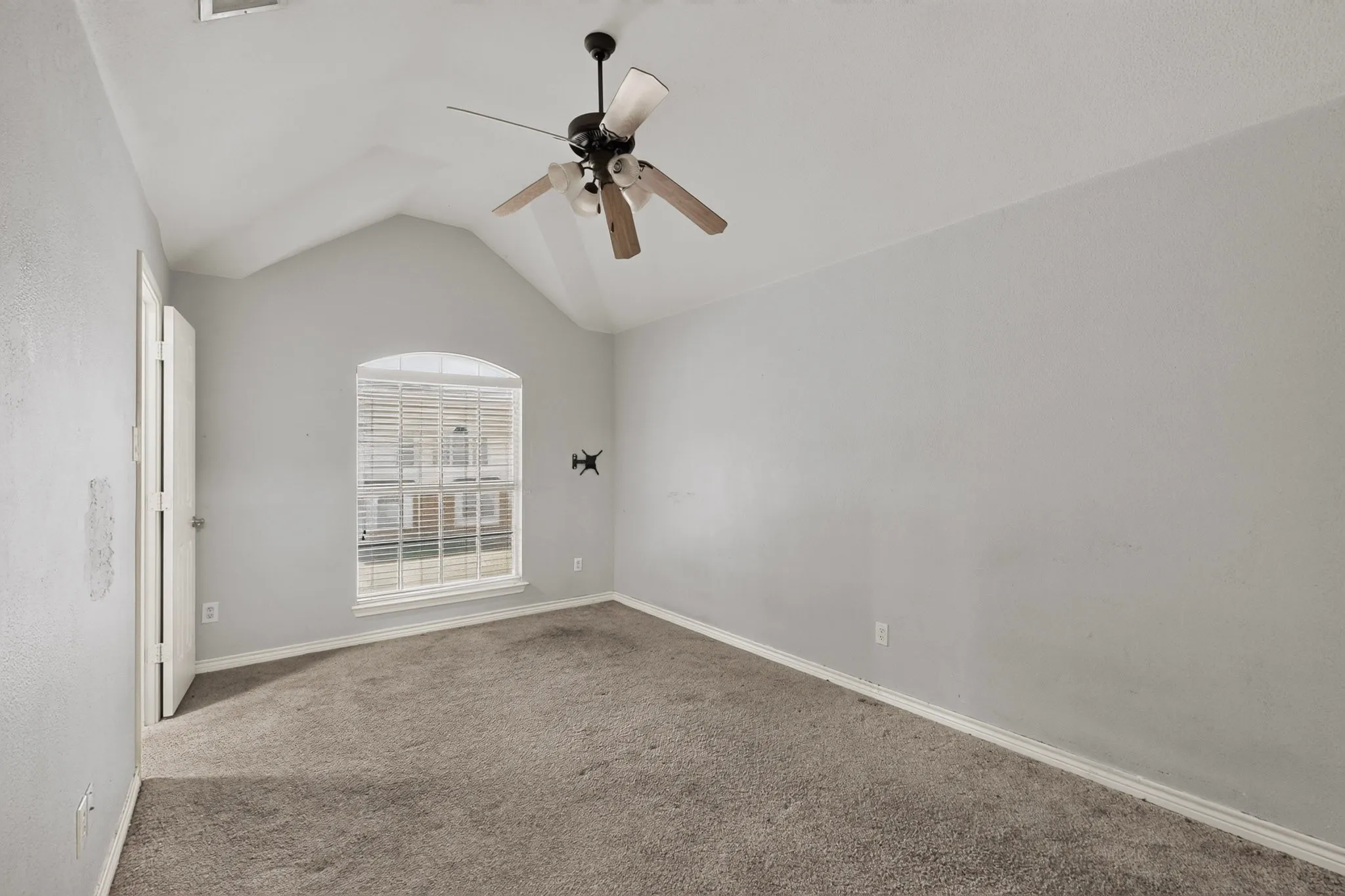 Vaulted ceiling with a ceiling fan, arched window with blinds, and carpeted flooring
