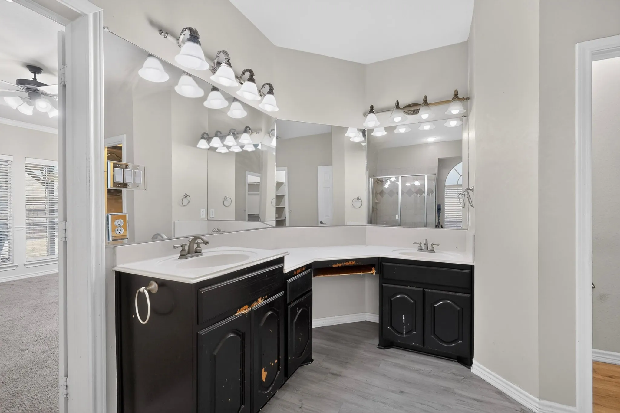 Dual-sink bathroom vanity featuring black cabinetry with bronze hardware, white quartz countertops, and brushed nickel faucets
