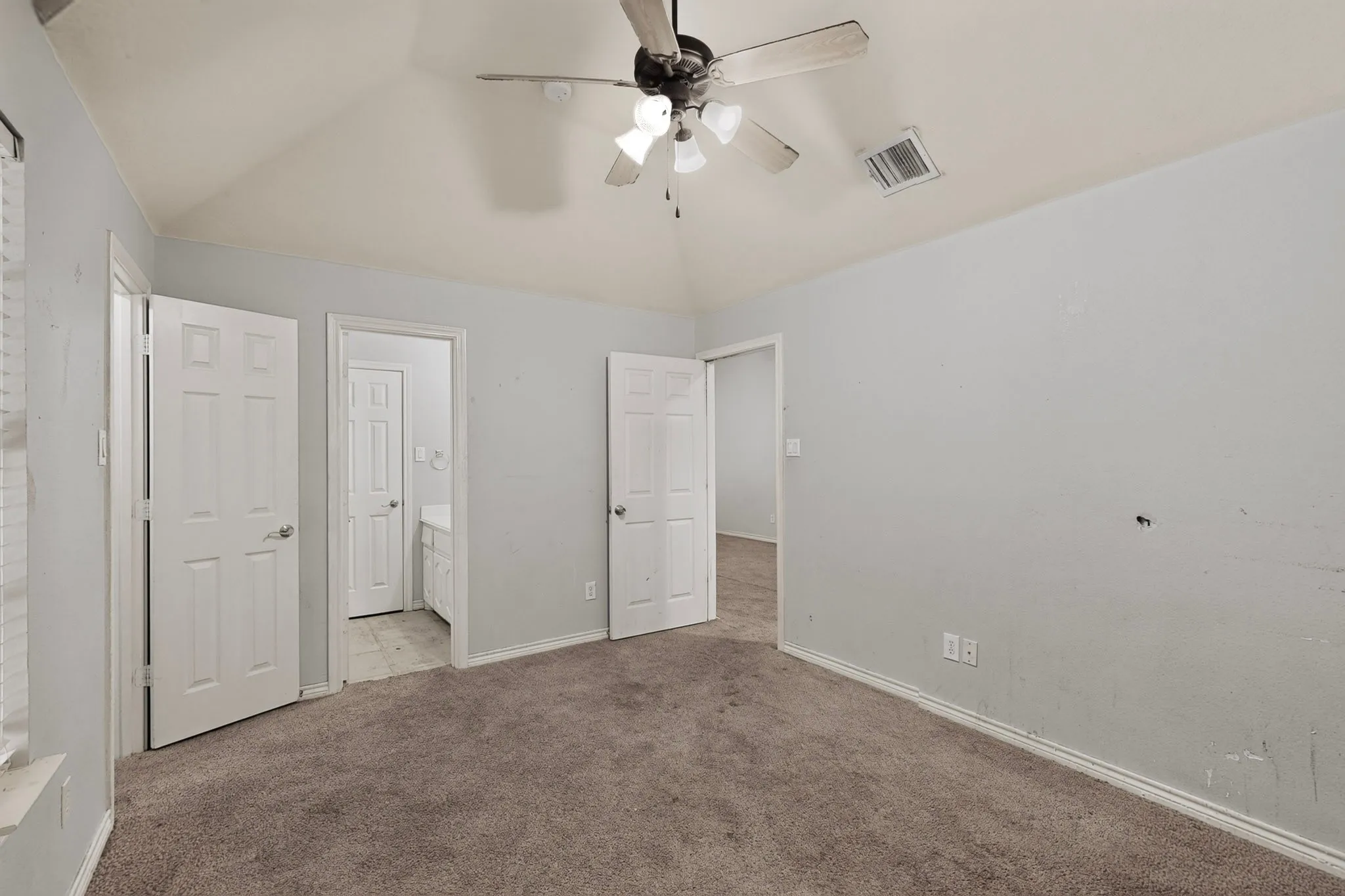 Vaulted ceiling with ceiling fan, light gray wall paint, and gray carpeted flooring