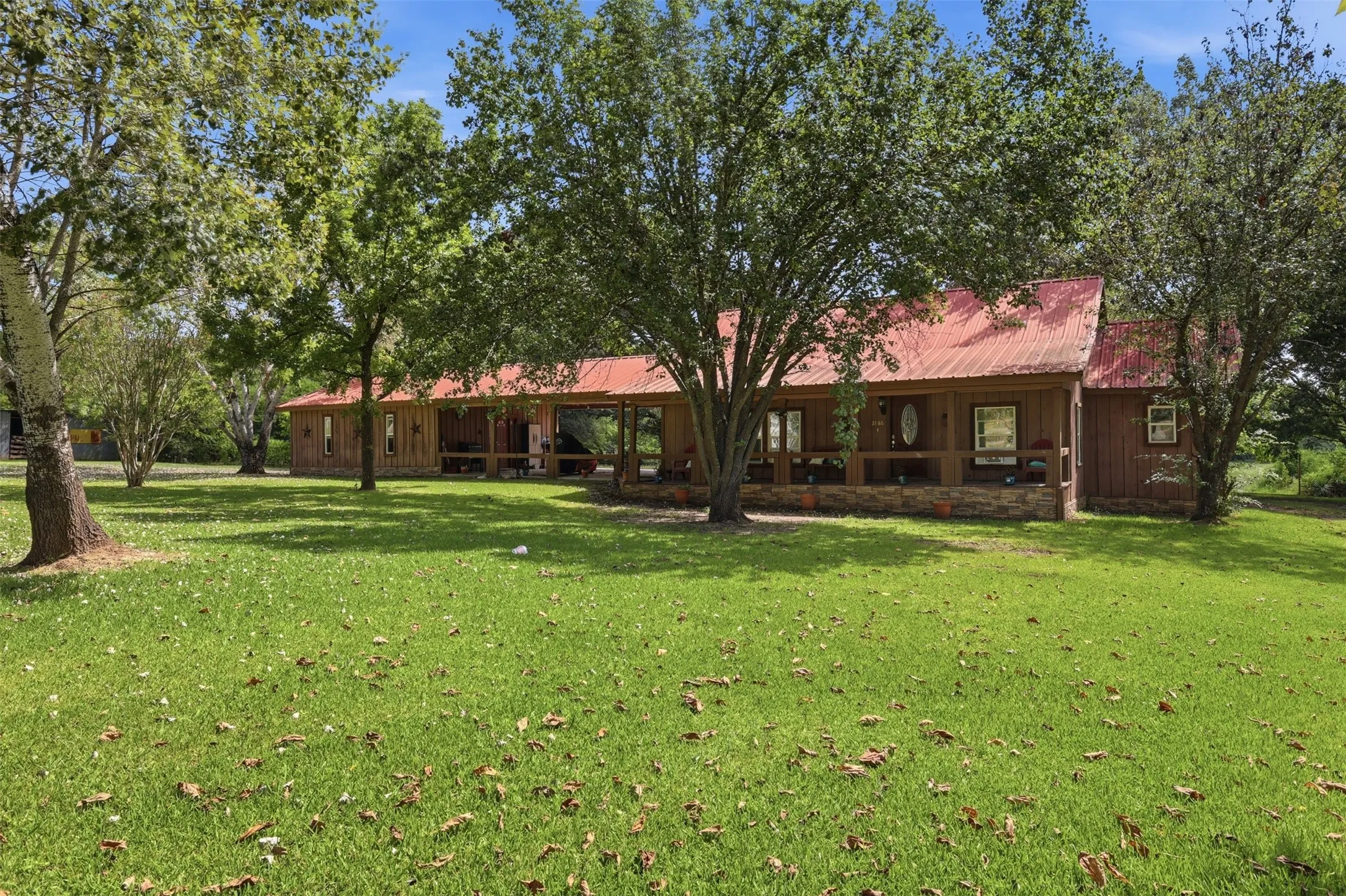 Lush grassy lawn surrounding the residence, shaded by mature oak and pecans trees.
