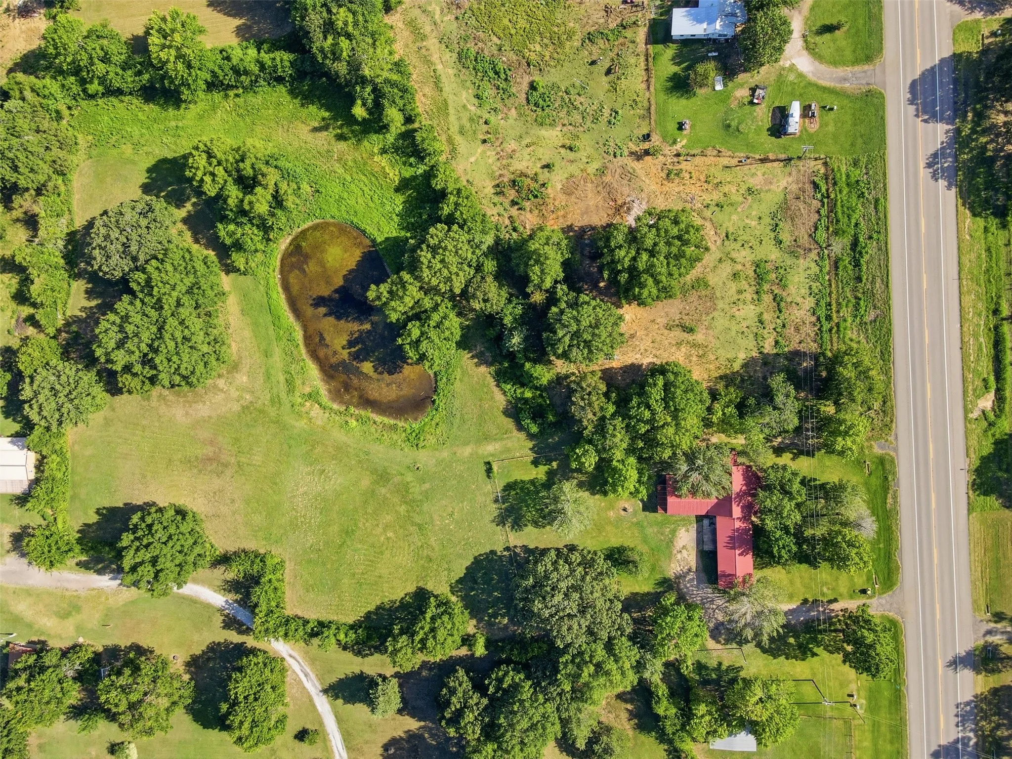 Overhead top-down aerial drone view showing the full property boundaries, pond, and road access.
