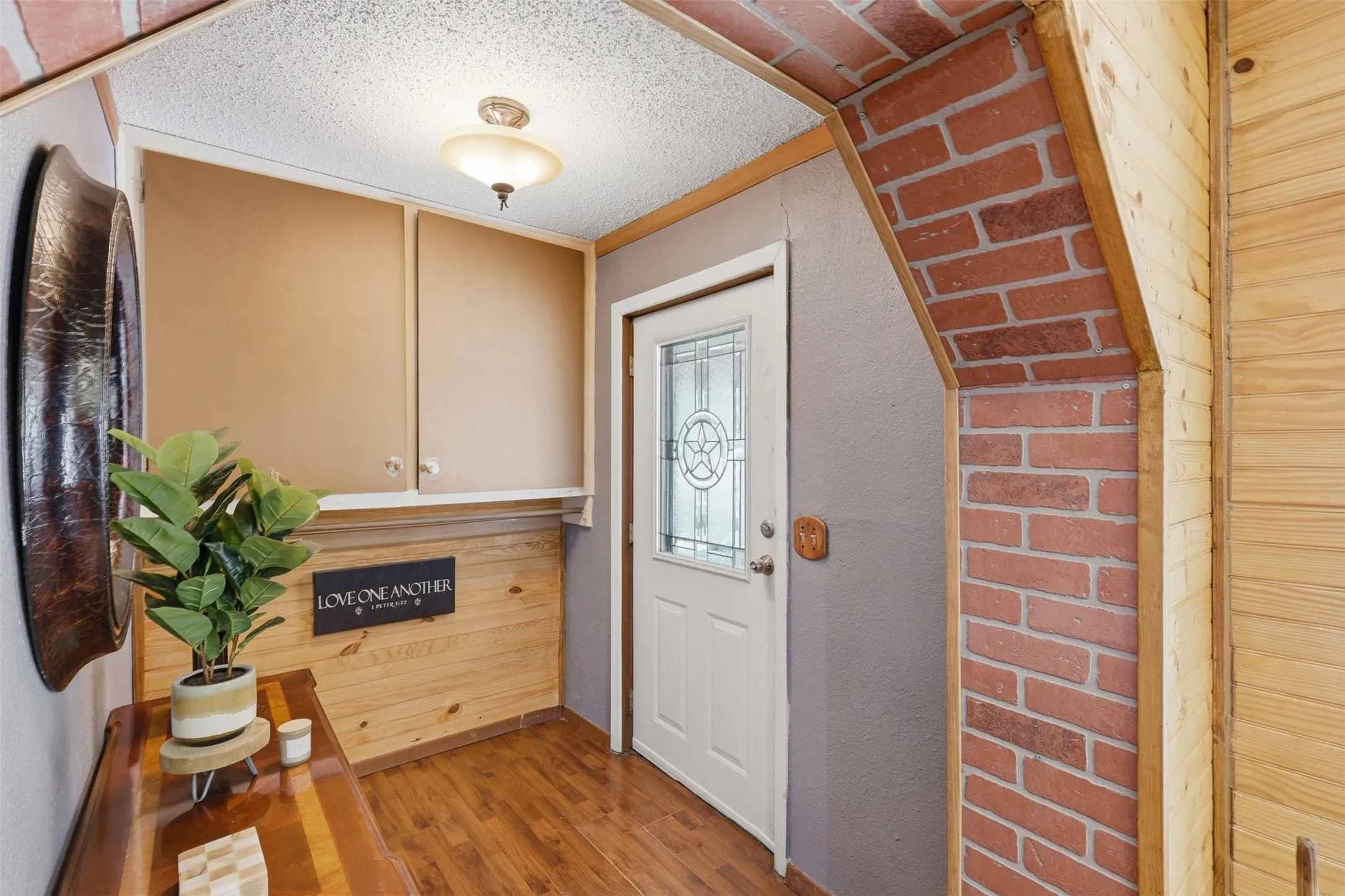 Interior entry foyer with tile flooring, warm wood paneling, and a brick archway transition.