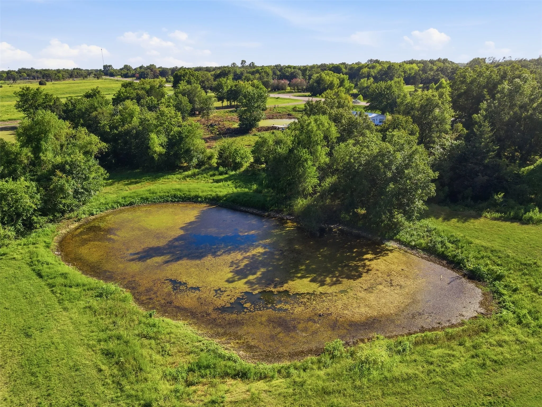 Aerial drone shot of the private stock tank pond surrounded by vibrant green pastures.