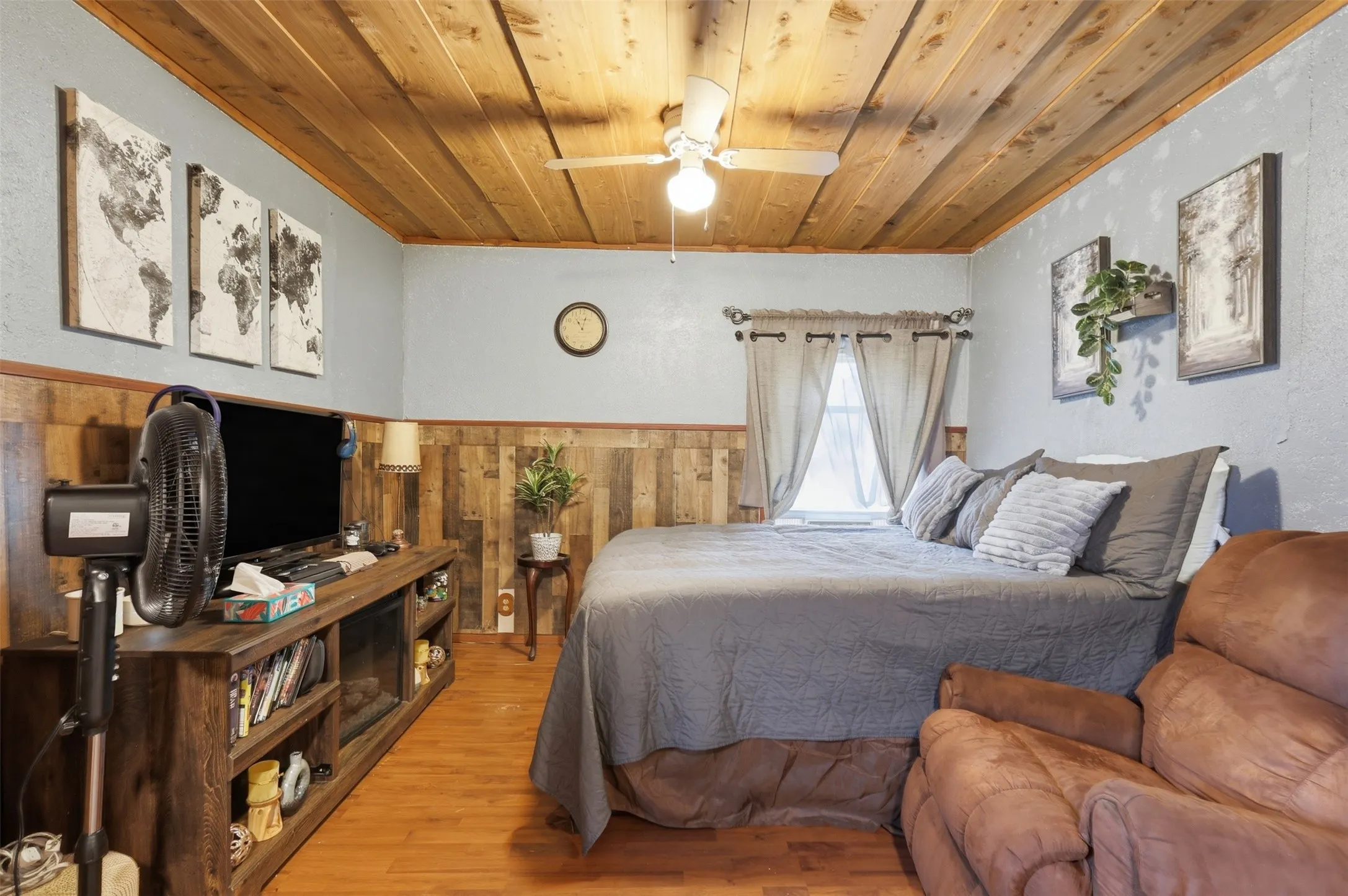 Cozy bedroom view displaying natural wood ceilings, rustic accent wall, and ceiling fan.